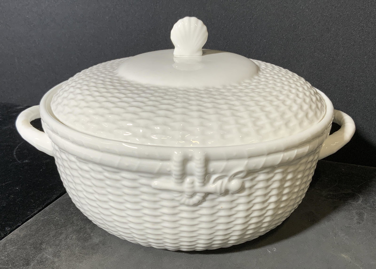 WEDGWOOD NANTUCKET Ceramic Tureen, England: Wedgwood lidded ceramic tureen. Crafted to resemble a woven wicker basket, finial lid resembles a scallop shell. Underside reads as WEDGWOOD BONE CHINA NANTUCKET, GEO. DAVIS, MADE IN ENGLAND, WEDGWOOD