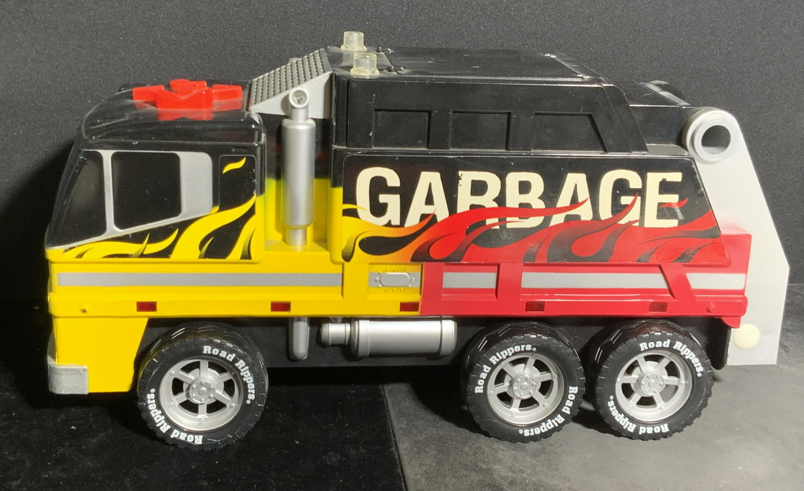 TOY STATE INDUSTRIAL Sanitation Garbage Truck Toy: A composite and plastic material childrens toy. Decorated with flames along the sides. Buttons to top. Obverse reads Sanitation Department, sides read Garbage, tires read Rod Ripper. Underside reads T