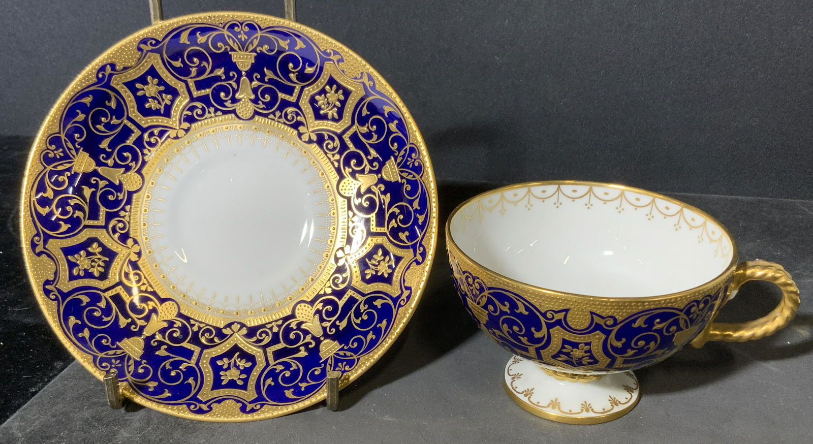 CAULDON Tea Cup & Saucer: Tea cup and saucer, underside reads as Cauldon England. Colored with cobalt and gilt paint. Wear is consistent with age. Largest piece measures approx inches 5.5 inches in diameter. Tea cup, server se