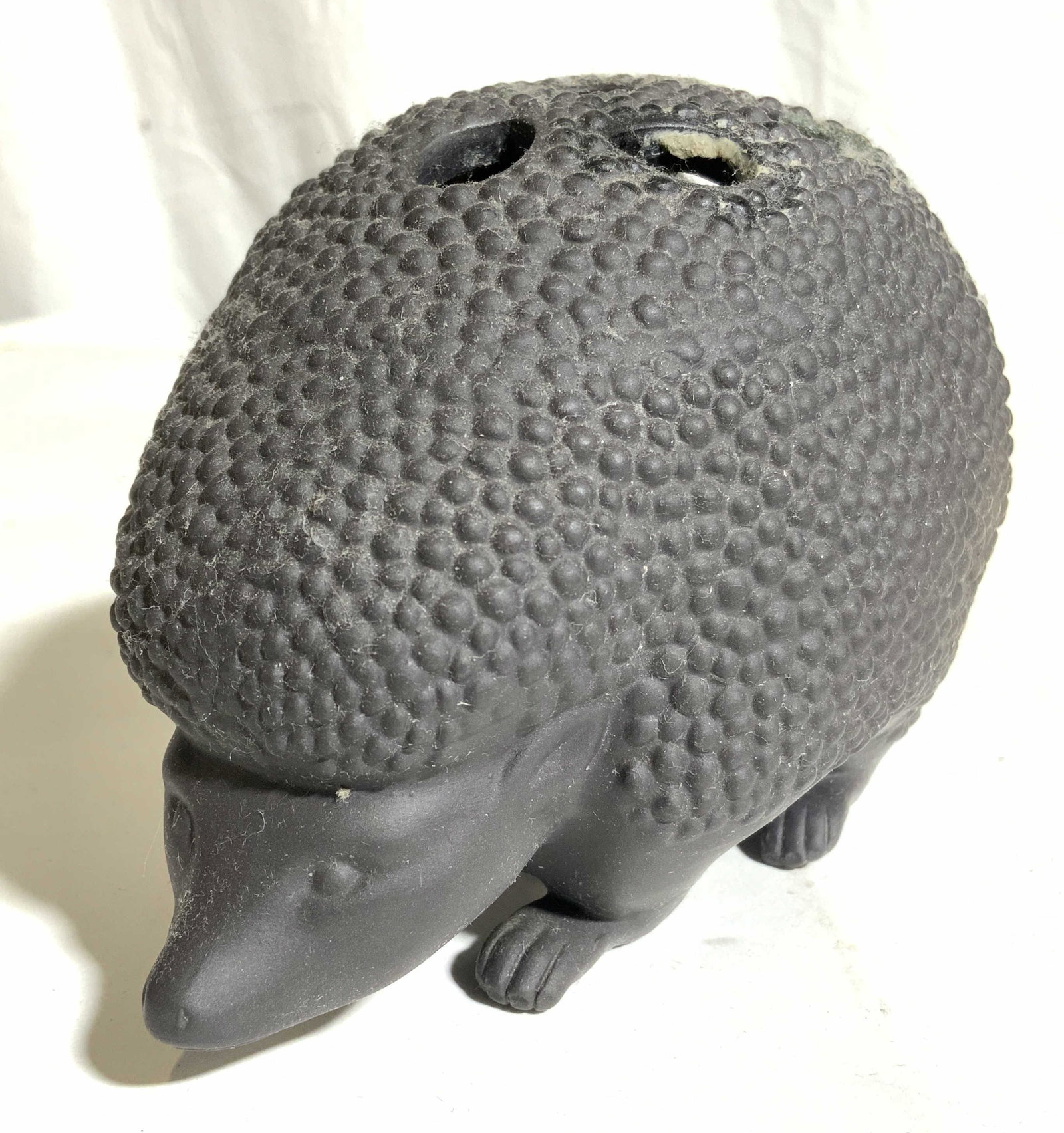 Composite Hedgehog Writing Utensil Holder: Pen holder appears to be composite, possibly porcelain. Piece is in the shape of a hedgehog. Top of pencil holder has 10 holes. Piece measures approx 5.5 inches long3.5 inches tall 4 inches wide. Pen 