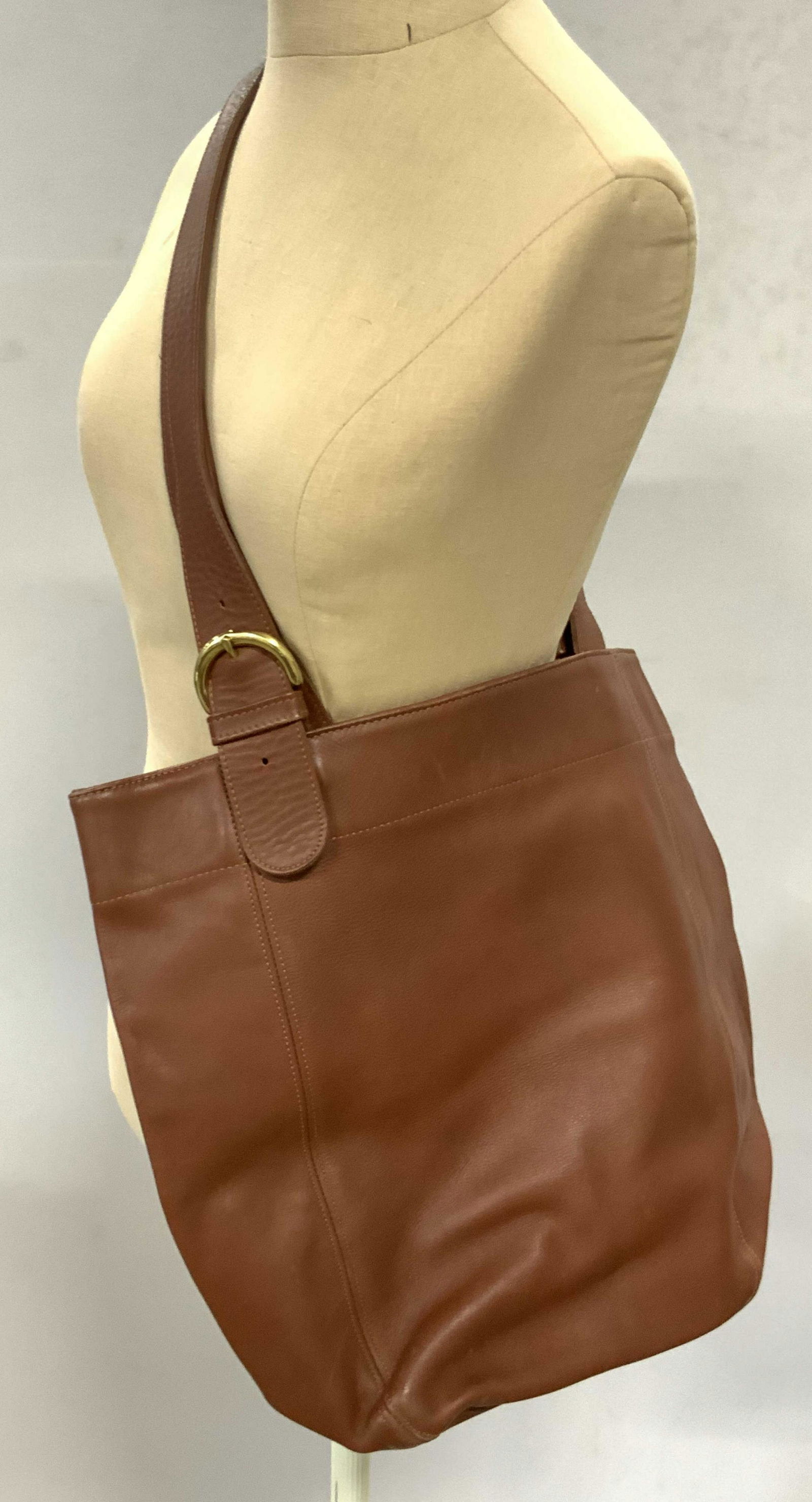 COACH Brown Cowhide Carry All Tote Bag: A brown hued cowhide carry all tote bag with gold tone metal hardware. Snap button closures. Interior reads Coach. Piece has surface wear consistent with use. Some scratches. Discoloration to undersid