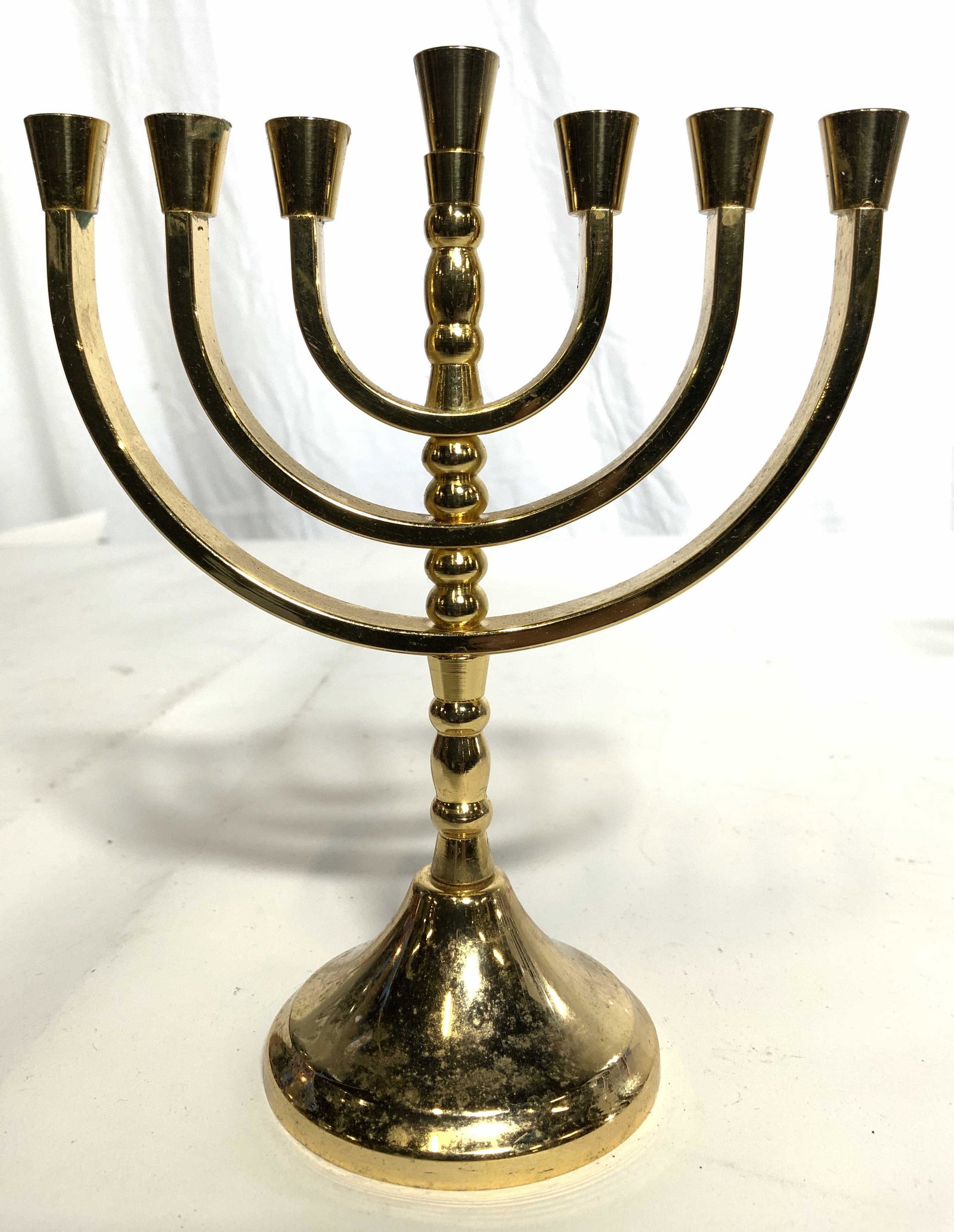 KARSHI Brass MENORAH: Underside of menorah is tagged KARSHI HAND MADE IN JERUSALEM. Menorah is gold toned and brass. Piece has circular shaped base. Piece measures approx 6 inches tall 5 inches wide. Menorah, brass menorah