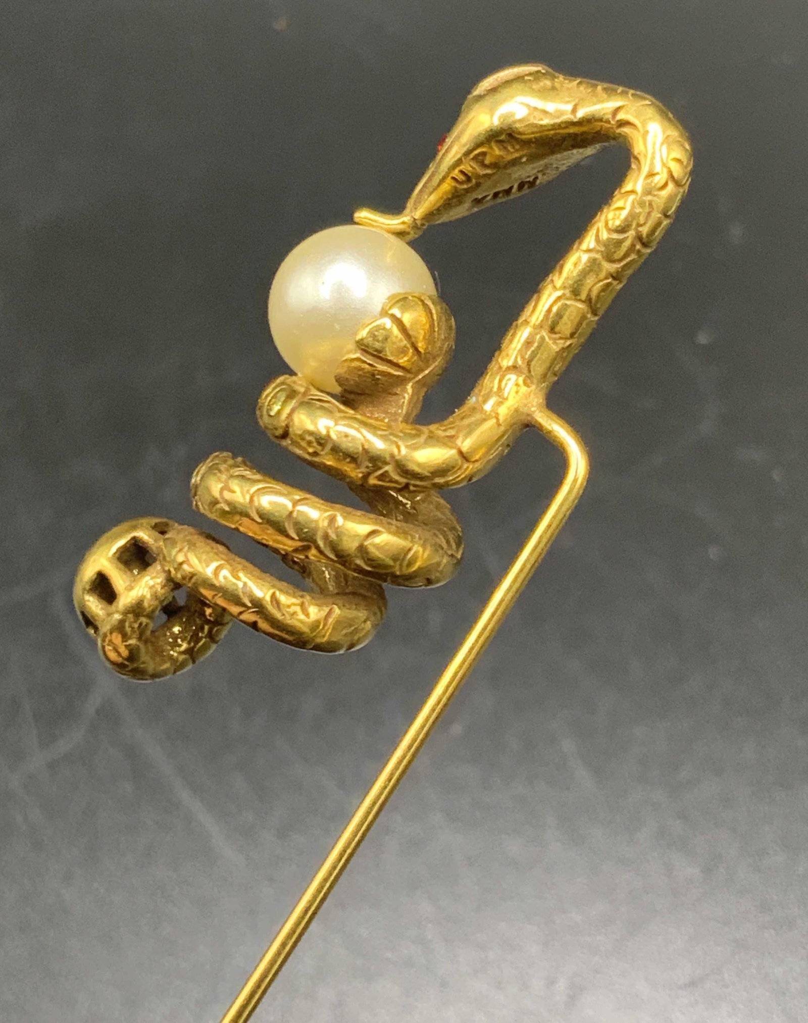 Vintage MMA UPM Bejeweled Serpent Sweater Pin: A vintage gold tone metal sweater pin adorned with faceted crystals along a serpent / snake figure. The snake is coiled along a pearlescent bead. Underside signed MMA UPM. Some wear consistent with vi