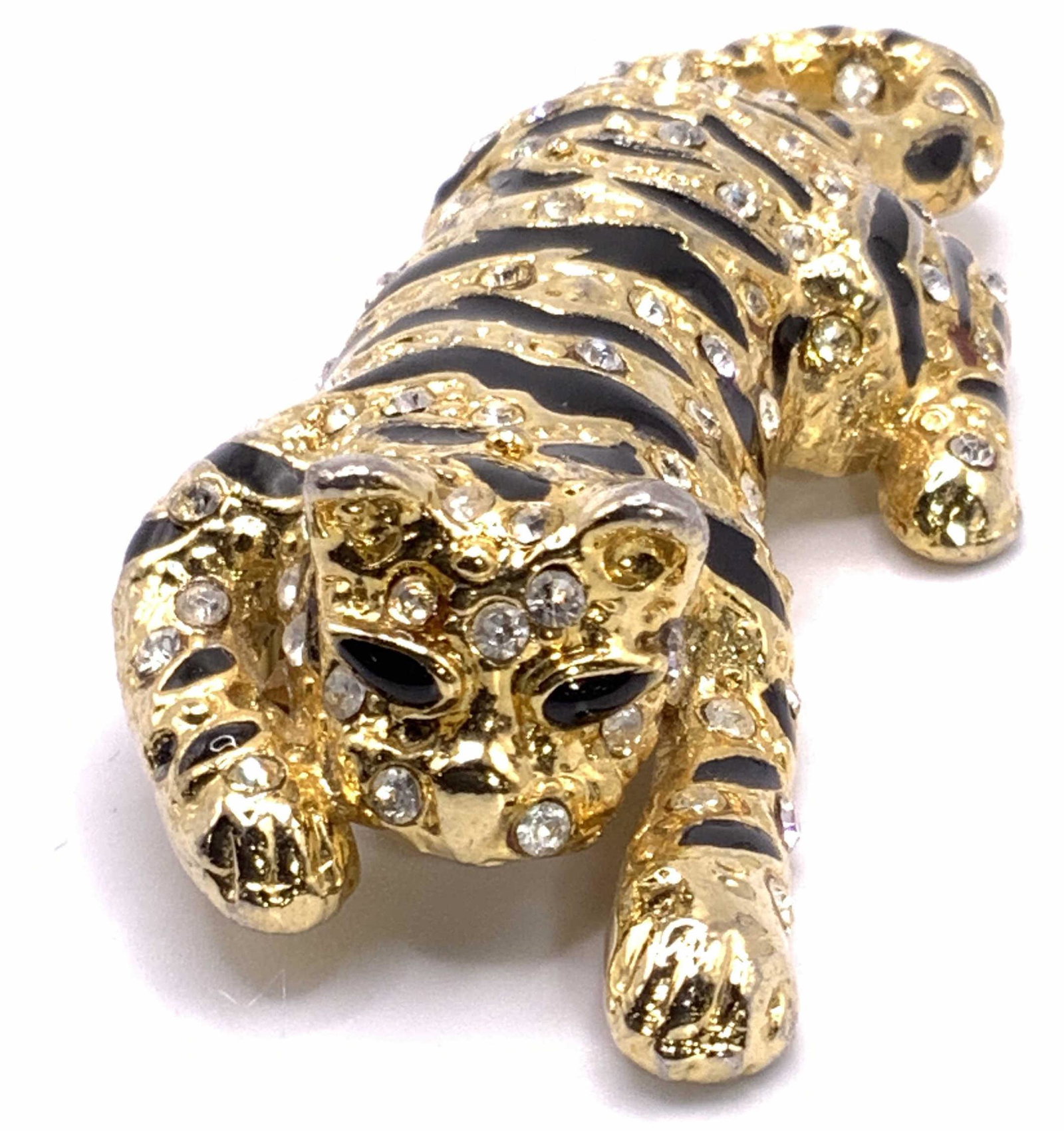 Vintage Bejeweled & Enameled Tiger Form Brooch: A gold tone metal bejeweled & enameled tiger / big cat form brooch. Colorless faceted crystals & black enamelwork throughout. Raised & impressed metalwork. Underside possesses metal pin closure. Measu