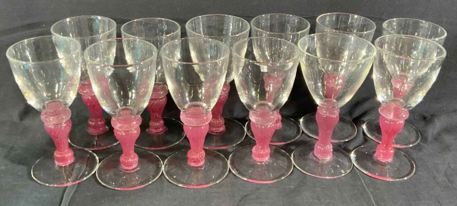Set 12 A. HAY Signed Crystal Pink Stemmed Goblets: Twelve clear and pink handcrafted artisan crystal goblets. The pieces feature twisted pink stems. Pieces have some weight. Varying sizes consistent with handmade quality. Largest measures approx 8H x 