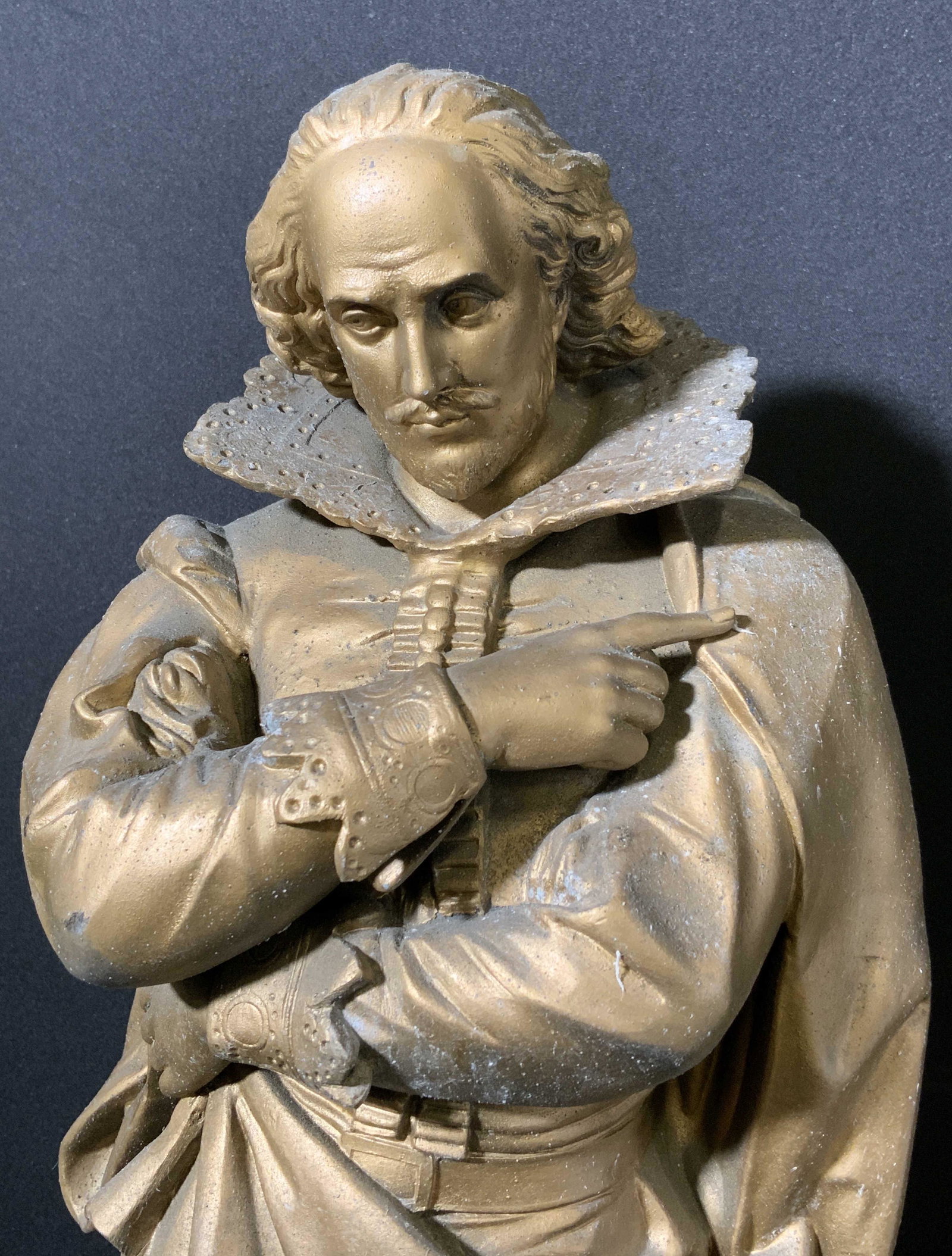 Cast Gilded Metal Elizabethan Nobleman Sculpture: Gilded metal sculpture of An Elizabethan era style nobleman. Sculpture is affixed to a wooden base, base has been colored black. Depicts a man grasping at his cloak, arms crossed across his body. Wear