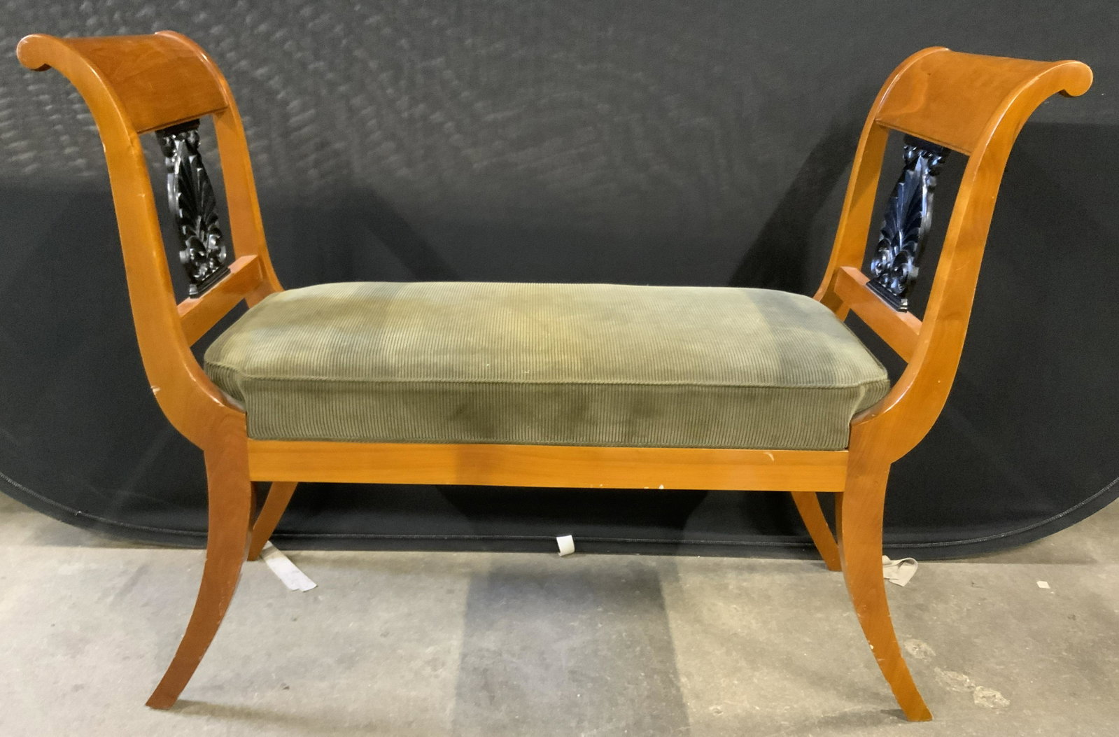 Upholstered Wooden Sleigh Bench: Wooden sleigh bench, possibly vintage. Upholstery is single welt, olive toned. Splayed legs. Carved wooden detailing sits below each arm. Wear is consistent with age and use, wear to edges and corners
