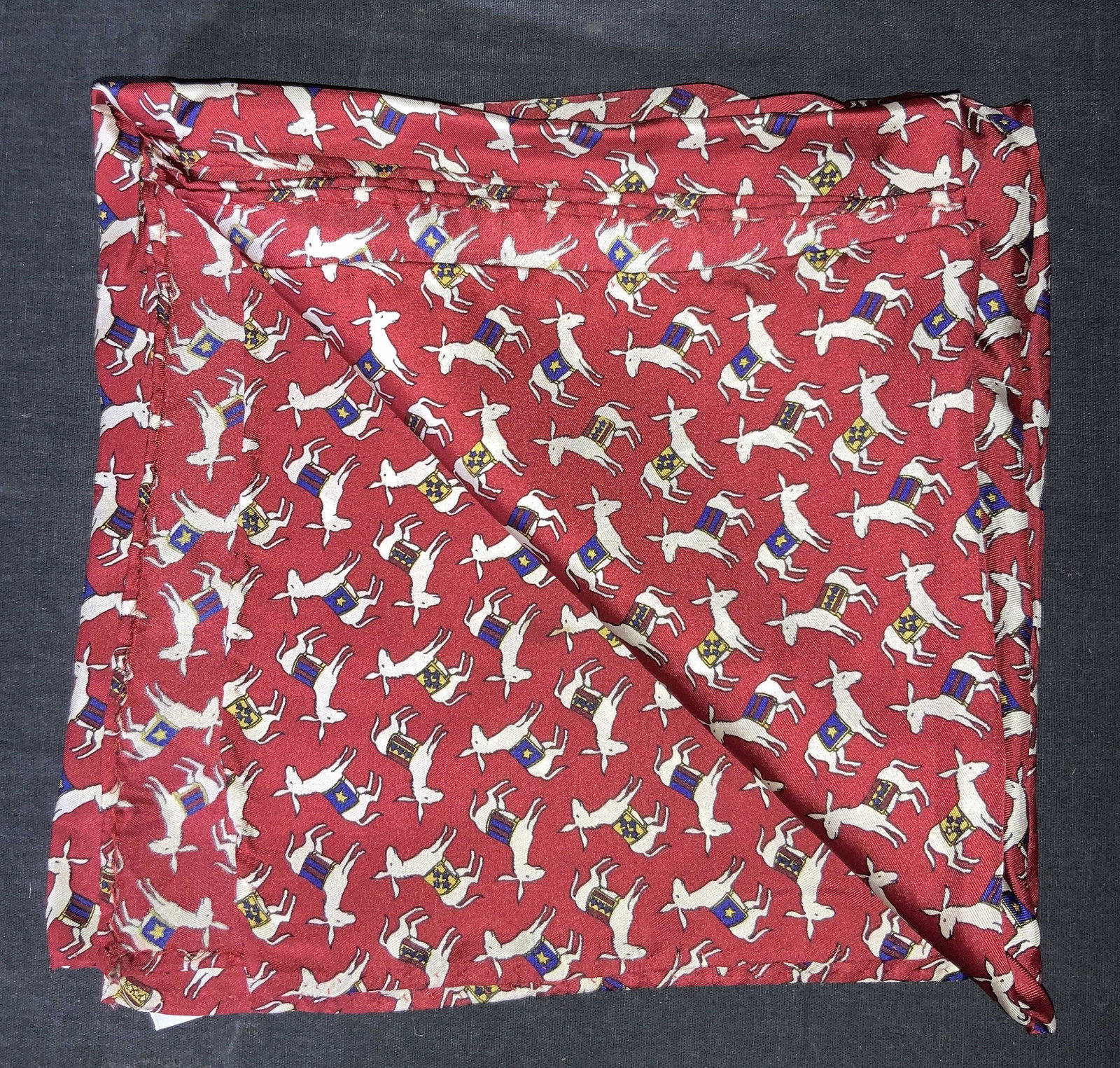 Silk Donkey Pattern Scarf: A scarf with a red base tone with depictions of donkeys wearing different colored saddles adorn the scarf throughout. Tag reads 100% Silk. Property of Manhattan, New York Estate of D. Winston, matchma