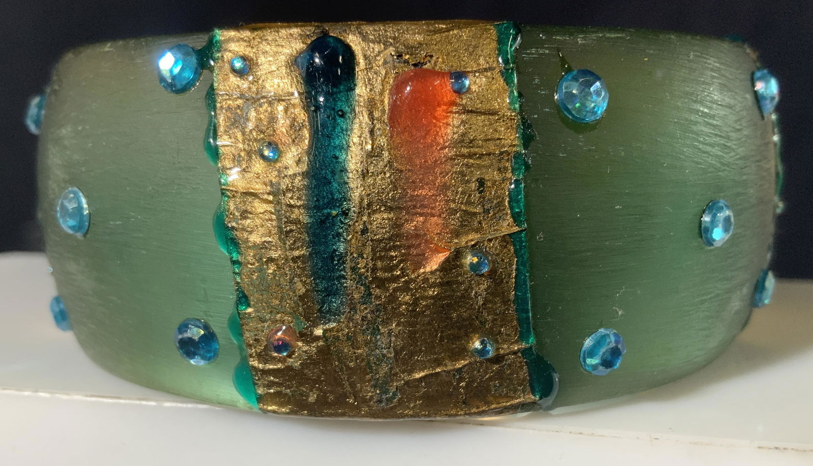 Hand Crafted Artisanal Chunky Bangle: Hand painted and decorated bangle , possibly on lucite or composite. Seafoam blue with added blue rhinestones, gold leaf and dripped glaze. Width 1 1/8 in. Diameter 2.5 in. Property of Manhattan, New