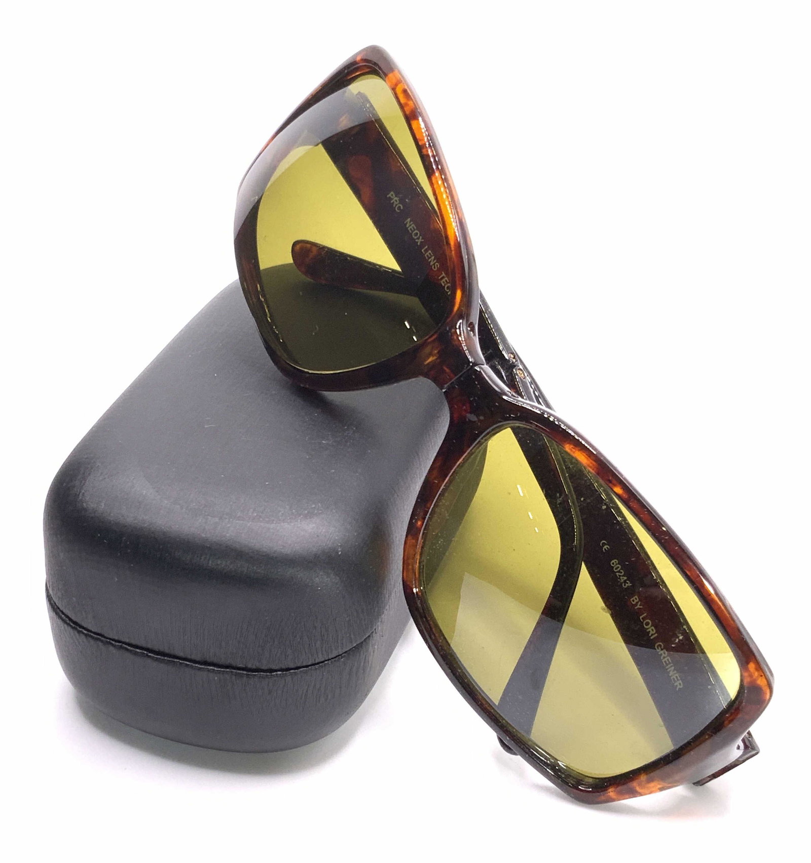 LORI GREINER Fashion Folding Sunglasses W/ Case: A pair of foldable sunglasses contained in their original packaging. Tortishell style brown hues. Interior of sunglasses reads LORI GREINER. Pamphlet reads Fashion Folding Sunglasses by LORI GREINER w