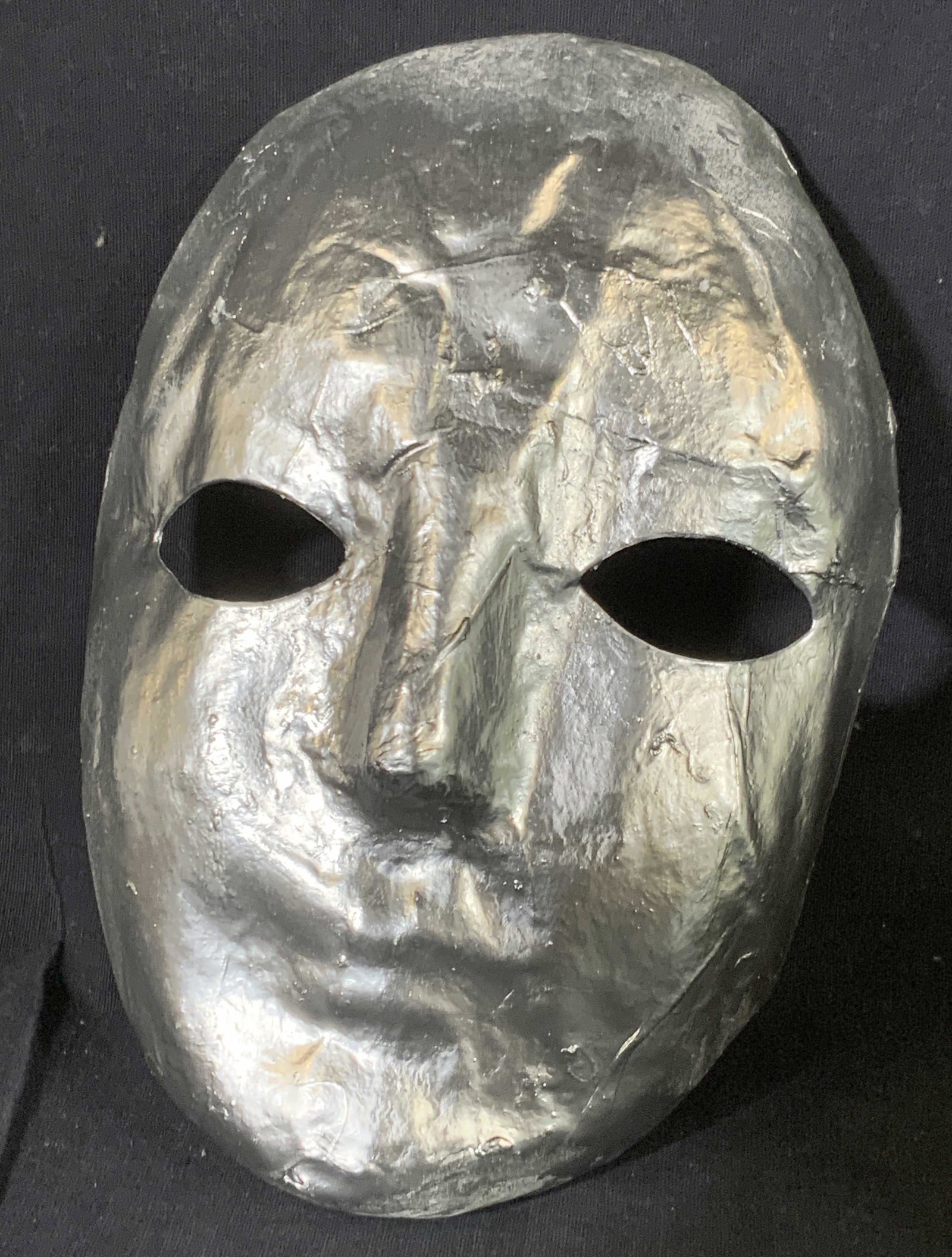 Handmade Papier-mache Metallic Face Mask: A handmade face mask, appears to be crafted from Papier-mache. Metallic silver tone finish. Measures approx 8H x 5W in. Some wear to finish. Face mask, metallic mask, wearables, collectibles, decorati