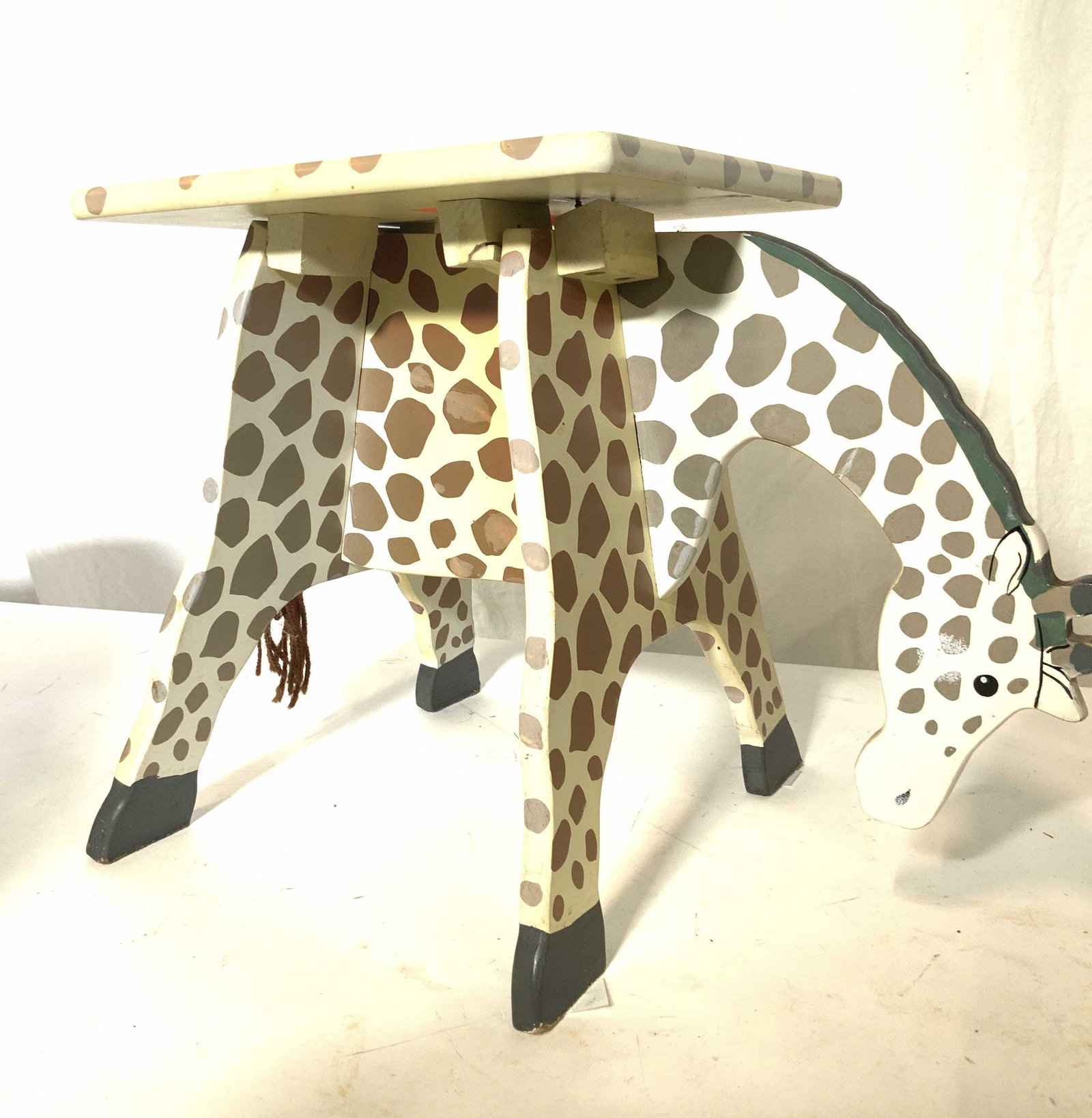 Arts and Crafts Kids Giraffe Stool: Hand Painted Wood Stool, in form of Giraffe , has tail made of yarn. Stool stands 11.5 in. Ht. Seat is 9.25 x 8 in. Needs fastening of under pieces to secure. Currently wobbly and should be used for d
