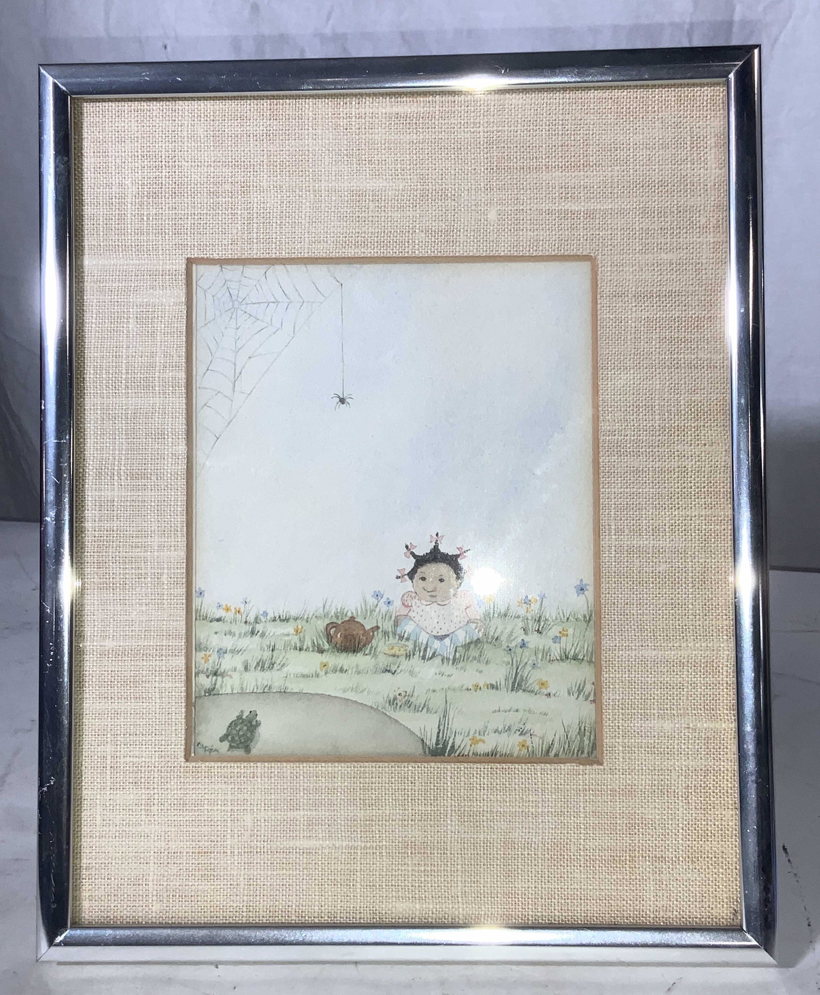 OLPEA Signed & Framed Watercolor Print: Watercolor on paper depicts a little girl sitting in the grass with a teapot, a spider web and hanging spider to the side. Water on stock paper, framed with tan linen mat and silver chrome frame. Fram