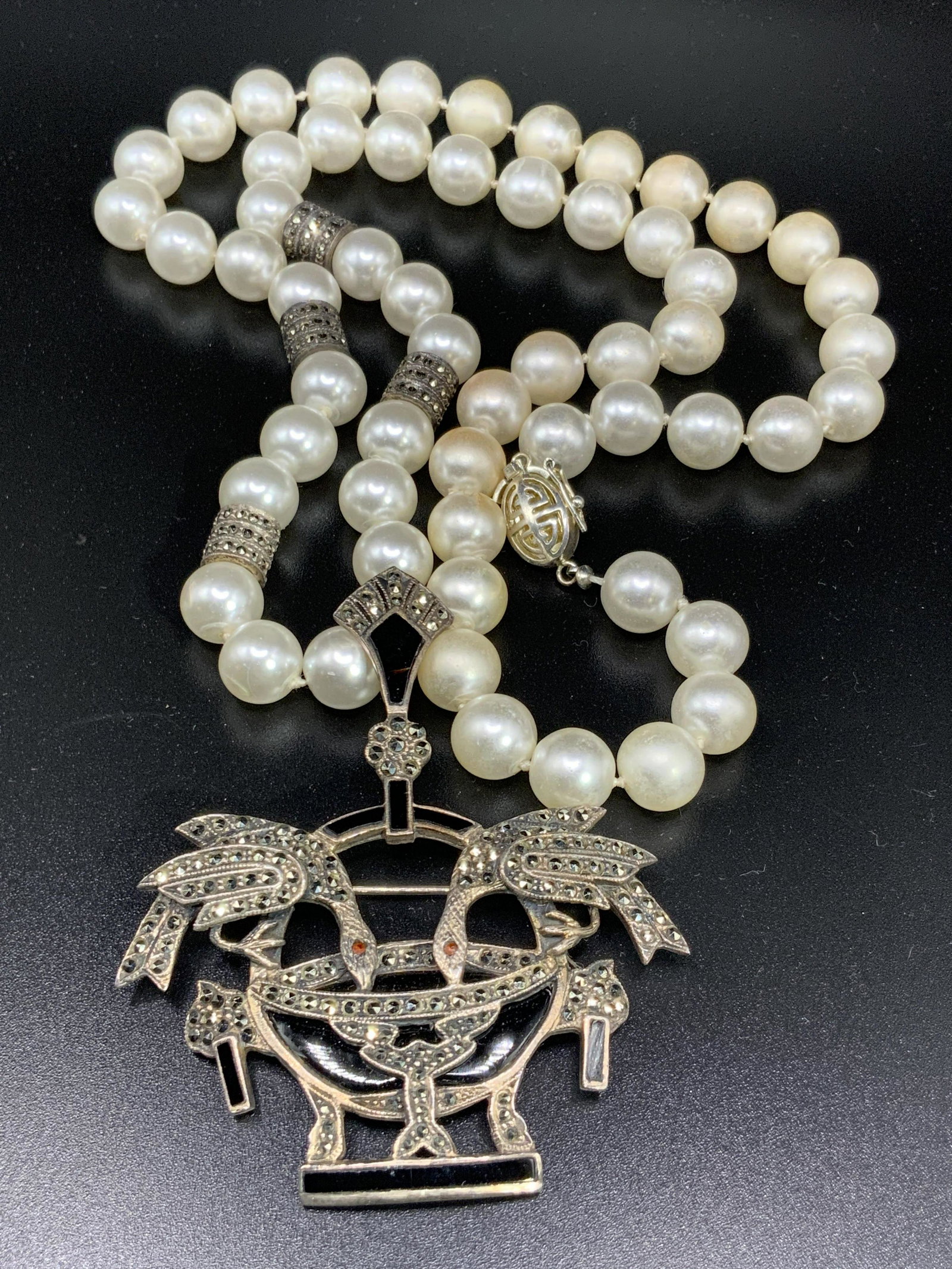 Vntg Pearlescent Enamel Marcasite Pendant Necklace: A vintage sterling silver pendant affixed to a pearlescent beaded necklace. The pendant features a bail and a pin closure on the underside. Marked 925 on underside. Obverse features black enamelwork a