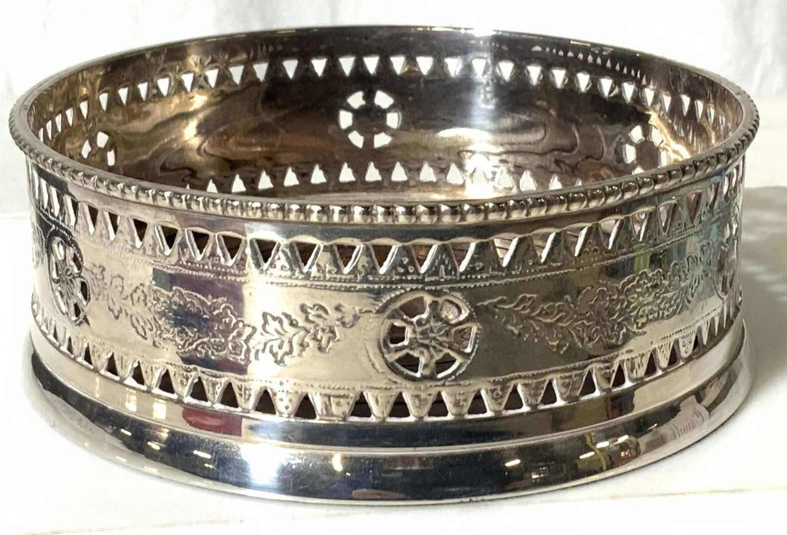 Silver Plate Etched Wine Champagne Bottle Coaster: Vintage Table Bottle Holder/ coaster with pierced And etched metal gallery and wood base. Bright and shiny with no evident tarnish. App 5 in. Diameter, 2 in ht. No marks Property of Trump Tower and Be