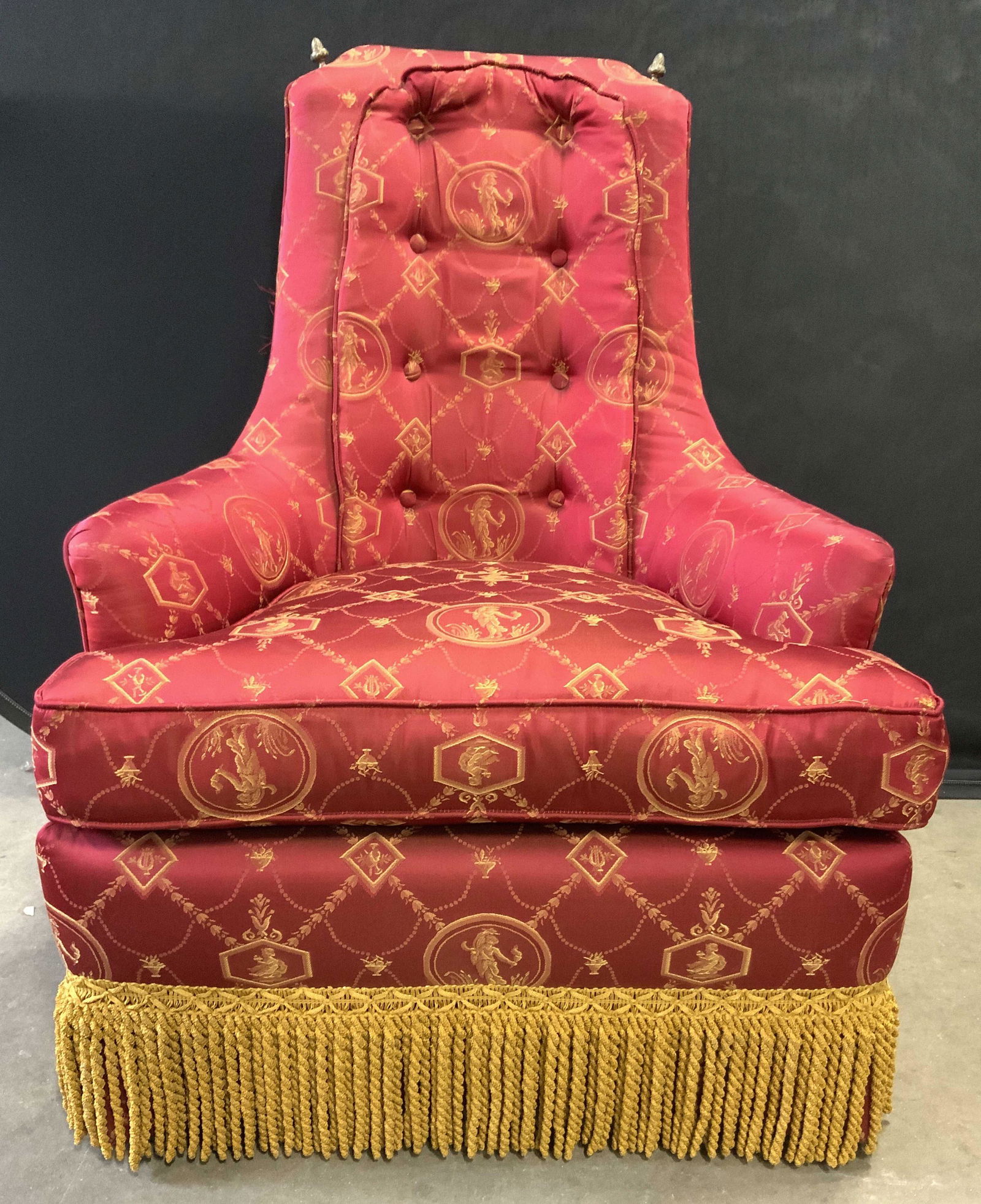 Custom Upholstered Armchair W Tasseled Skirt: Armchair is custom upholstered with red toned fabric with gold toned embroidered depictions of Figures, flowers, scrolls, harps & vases, in addition to geometric detail. Chair has goldenrod toned tass