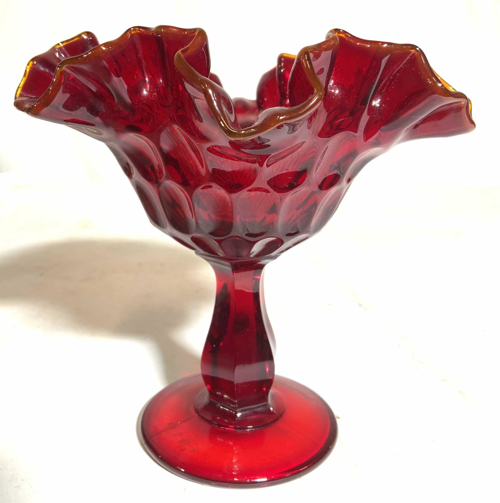 Fenton Style Frilled Pedestaled Glass Dish: In the style of Fenton glass, no apparent hallmarks or inscriptions. Dish is red toned with orange toned rim edge. Base is circular shaped. Dish appears to be handkerchief glass. Piece measures approx