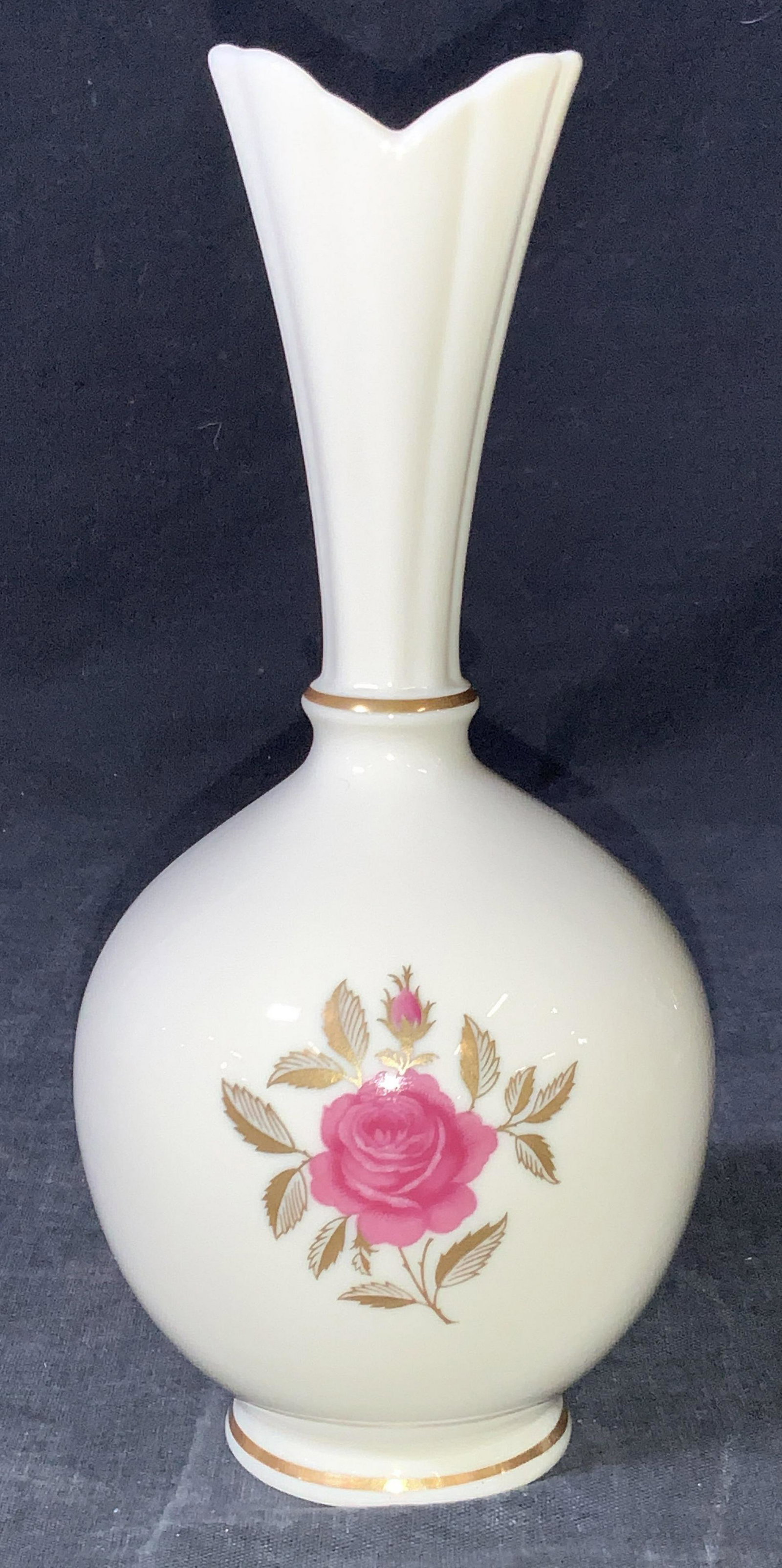 LENOX porcelain Cream Toned Rose Vase: A cream toned vase with a round body and flared neck and rim with a gold gilt band around neck and base, with a rose motif on obverse side of vase surrounded by gold gilding creating leaves. Marked Le