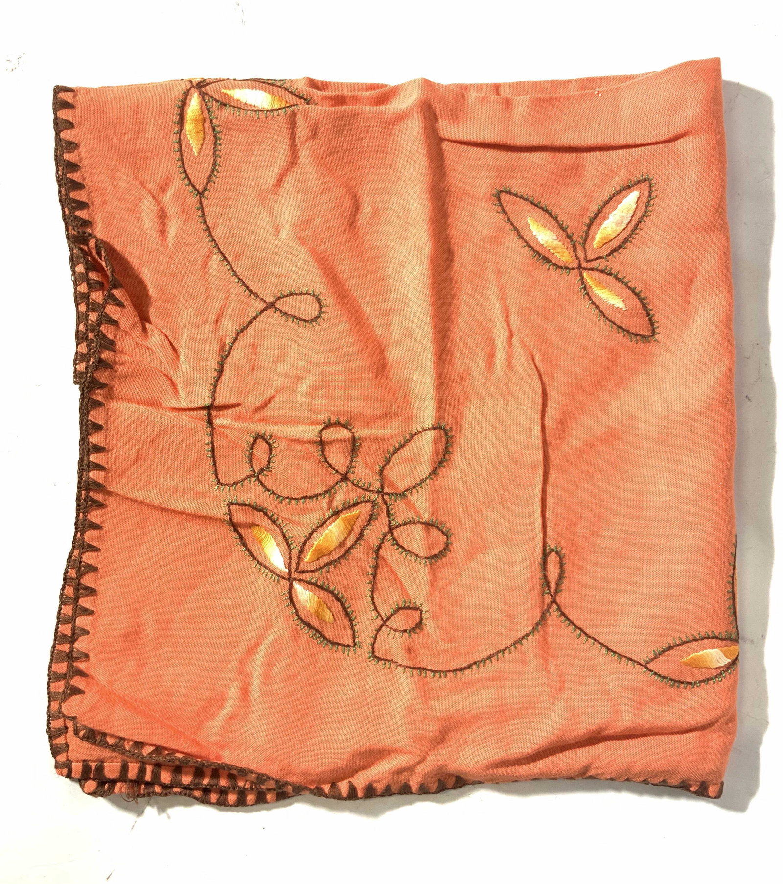Orange Embroidered Floral Table Linen: An orange table linen/ table cloth, soft hand, with a brown threaded edge design with green, brown and yellow threading embroidery to depict leaves and flowers on the corners of the linen. Property of