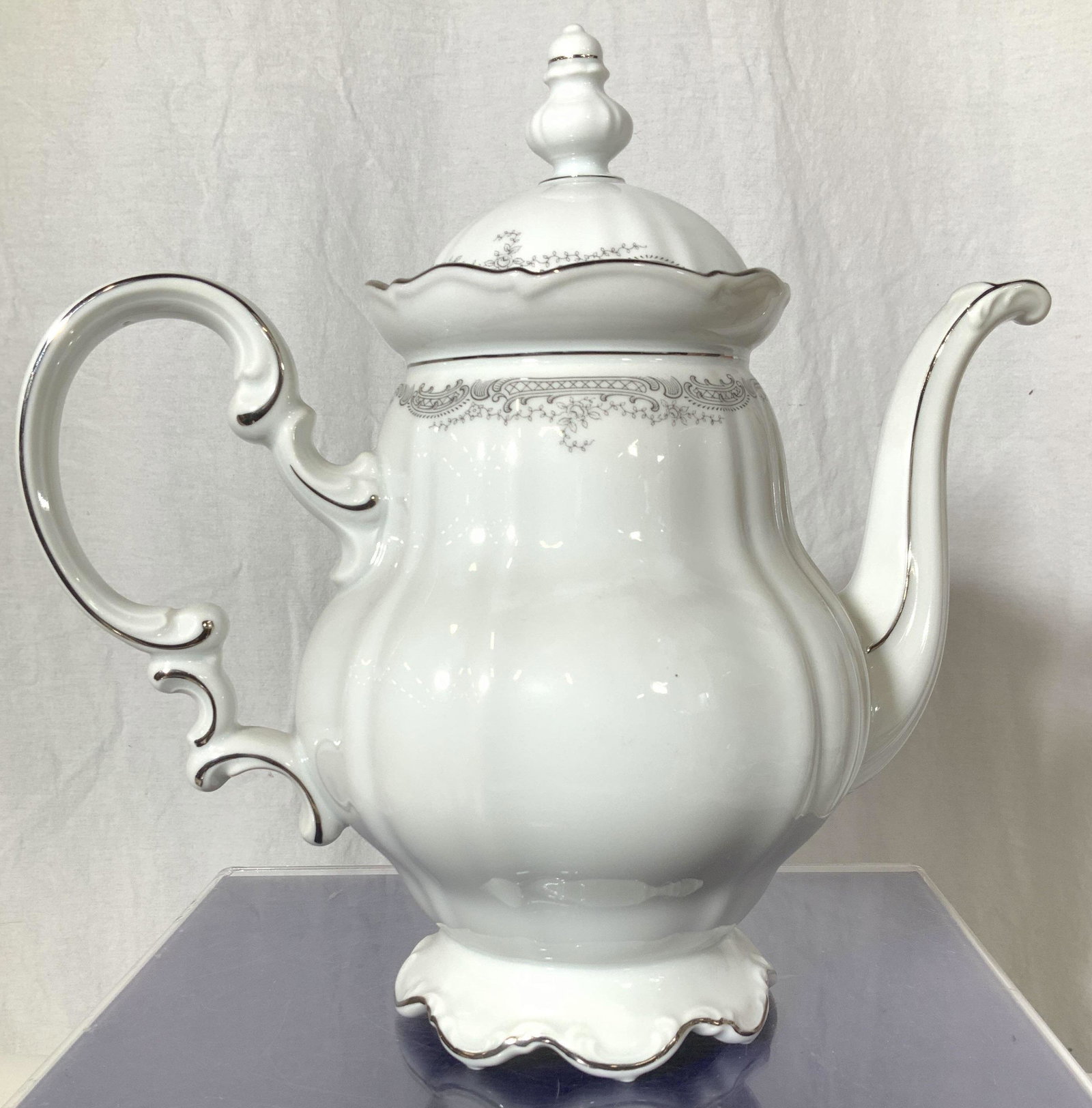 HUTSCHENREUTHER Sylvia lidded Tea/ Coffee Pot: Fine Bone Bavarian China made in Bavaria Germany. Lidded coffee pot or tea pot, white porcelain with grey scroll edge decor and silver plate rim. Scalloped edges. measures 10.5 in. total ht. , 11 in. 