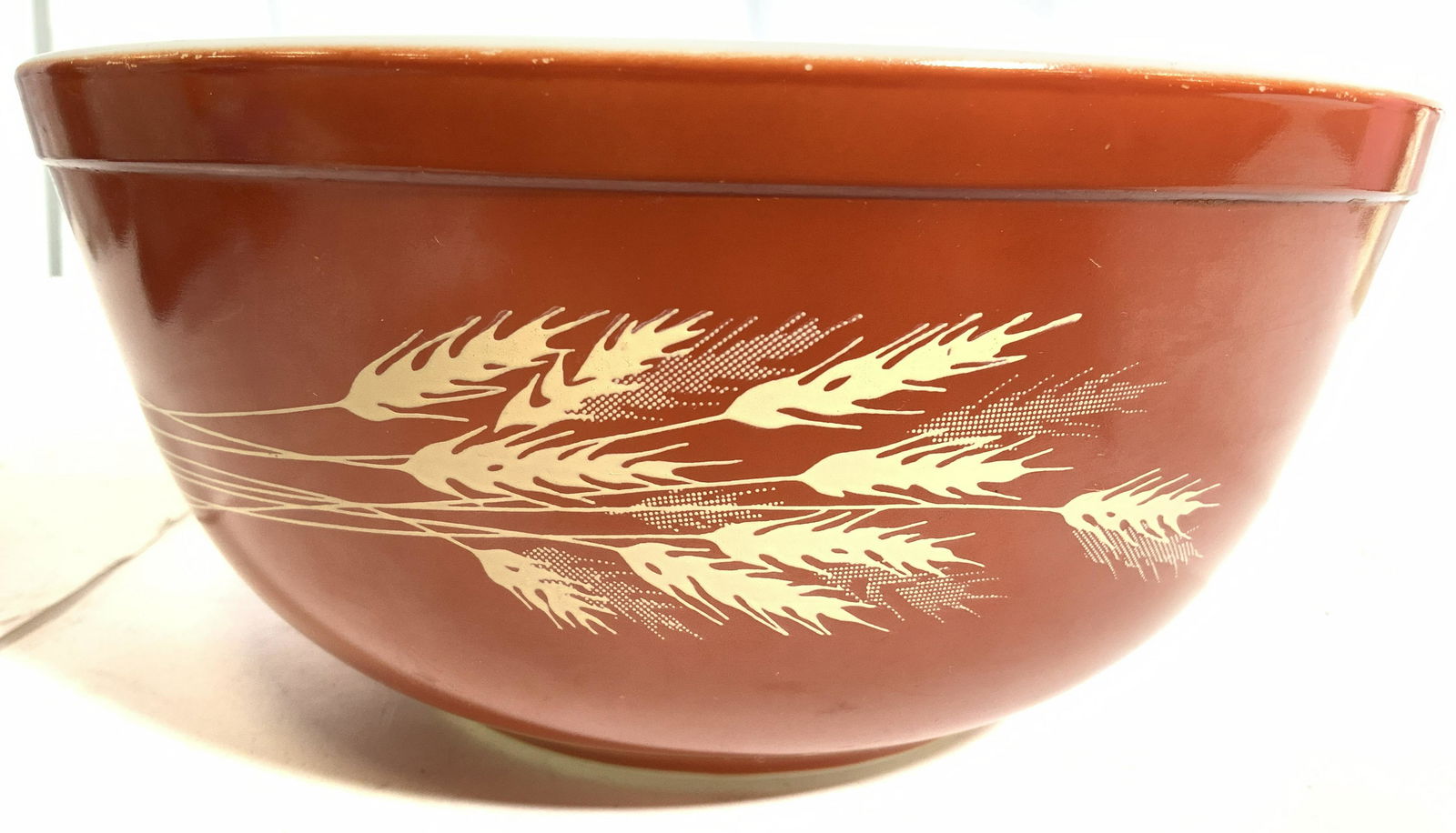 PYREX Mixing Bowl W Wheat Detail: Underside of bowl reads PYREX. Exterior is orange toned with tan wheat detail. Interior of bowl is white toned. Piece measures approx 9 inches wide 4 inches tall. Bowl, glass bowl, Pyrex bowl, mixing