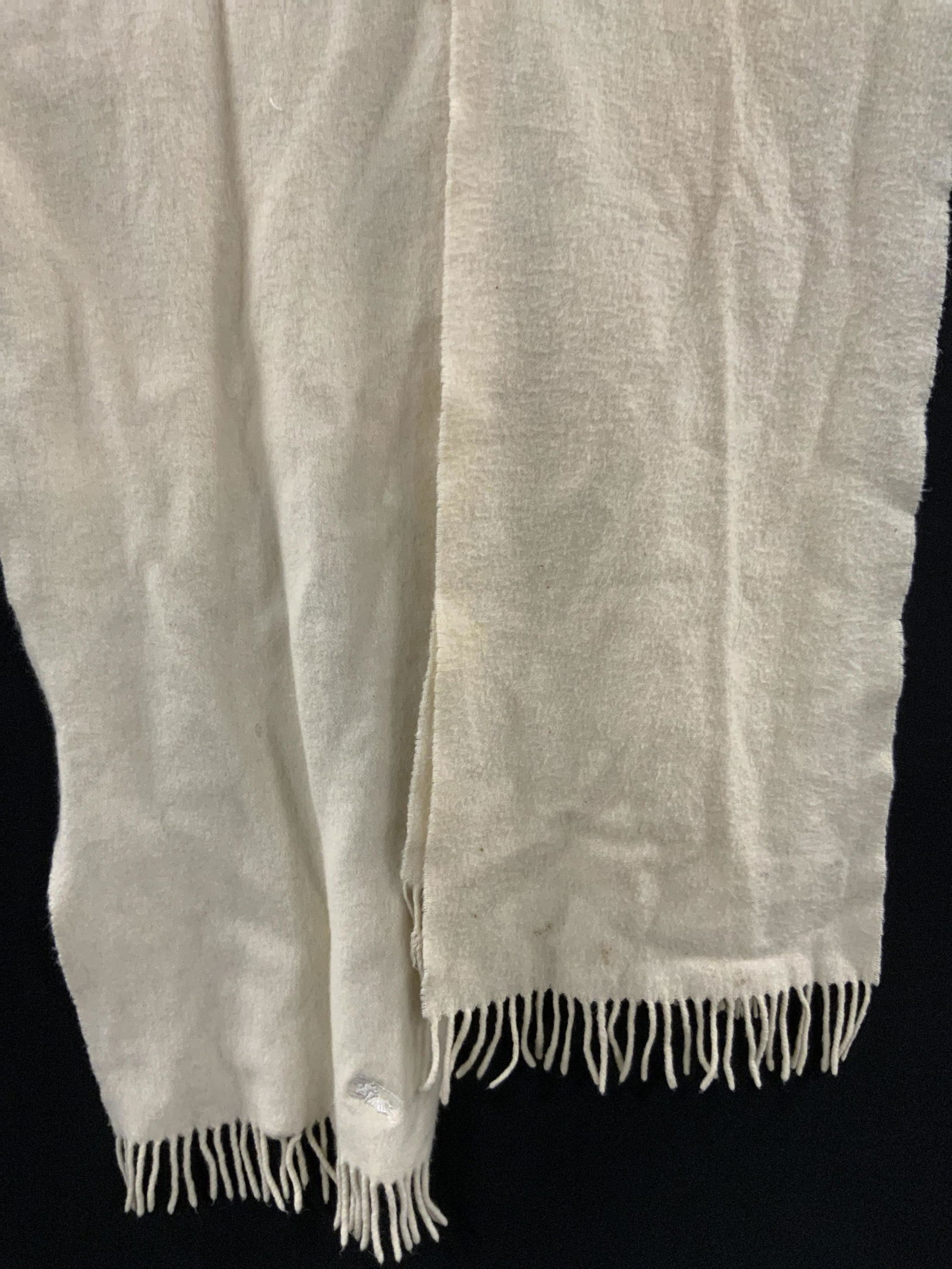 Lot 2 Vintage BURBERRYS Cashmere Scarves: Two cream hued BURBERRYS scarves crafted from cashmere. Tassel trim. One piece measures approx 52L x 11.5W in. Both tags read BURBERRYS CASHMERE MADE IN SCOTLAND. Some discoloration, residue, wear con
