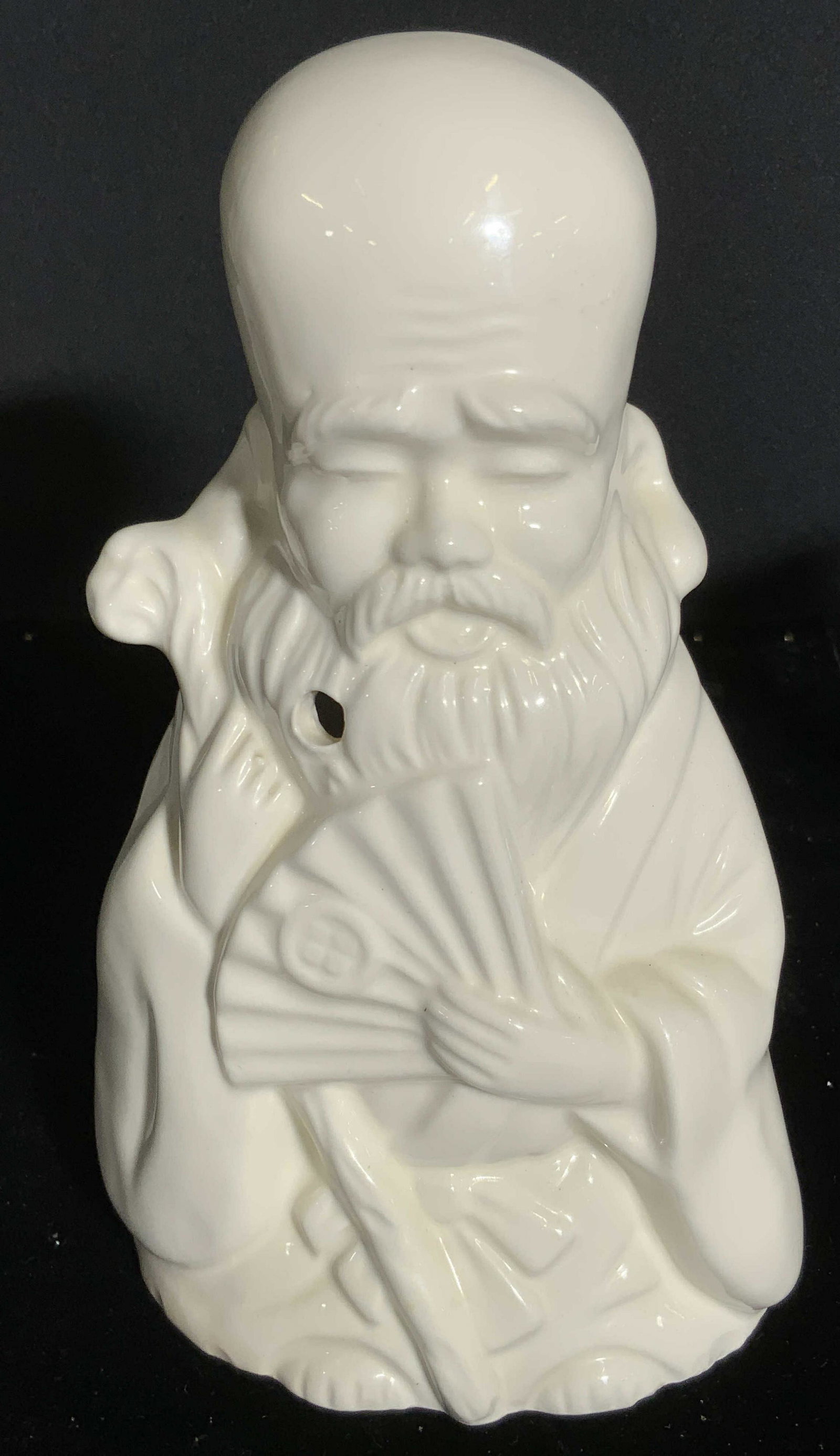 ORCHIDS OF HAWAII Sign Porcelain Male Figural Vase: A white glazed porcelain vase / Vessel crafted to resemble the form of a man holding a fan and a staff. Signed ORCHIDS OF HAWAII, Taiwan. Measures approx 8H x 5W in. Drilled hole to obverse, open back