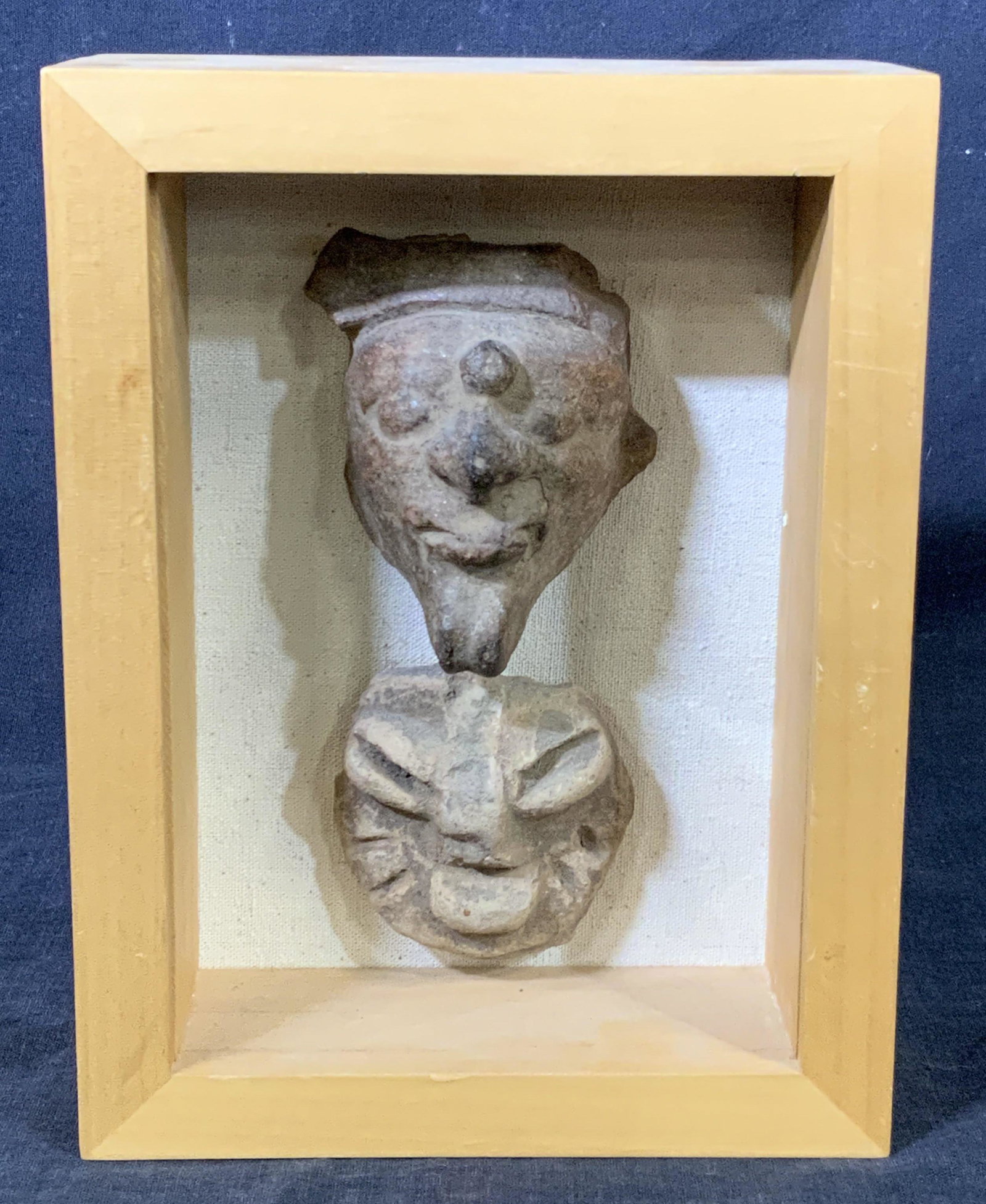 UMBRA Framed Clay Fascial Sculptures: A pair of fascial sculptures possibly formed by clay framed in a natural wood toned floater frame attached to back canvas by Umbra USA inc. Sculptures resemble faces of men. Reverse has back panel wit