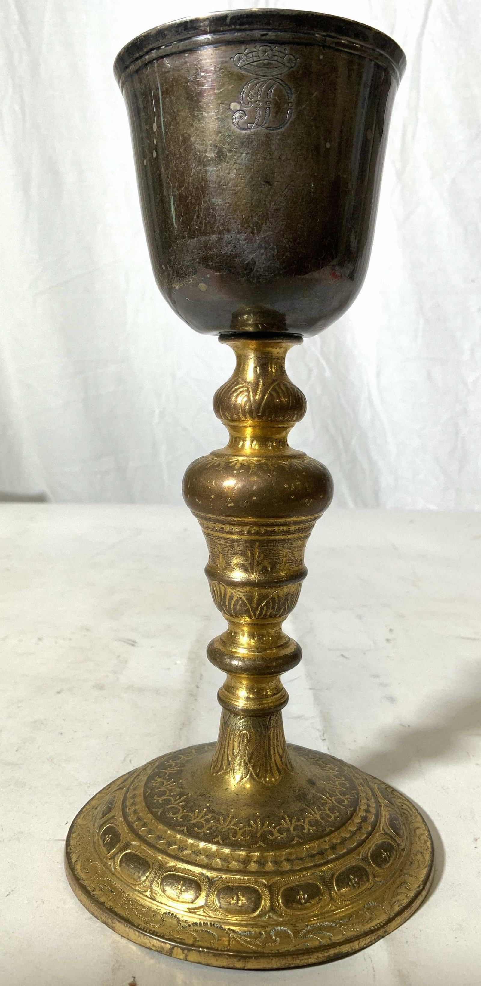 Vintage Gilded White Metal Goblet: Goblet has gold toned stem with intricate relief detail. Basin is silver toned white metal with D monogram on front. Base has circular shape. Piece measures approx 8 inches tall 4 inches wide. Goblet,