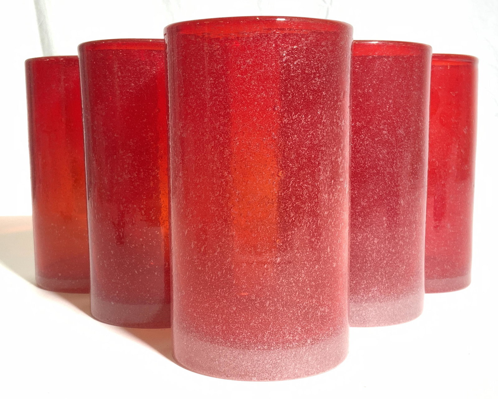 Set 5 Art Glass Vessels: Lot includes 5 vessels. Each are red with bubble speckle detail. Vessels appear to possibly be candle holders. Each piece is cylindrical shaped. Vessels each measure approx 6 inches tall 3.5 inches wi