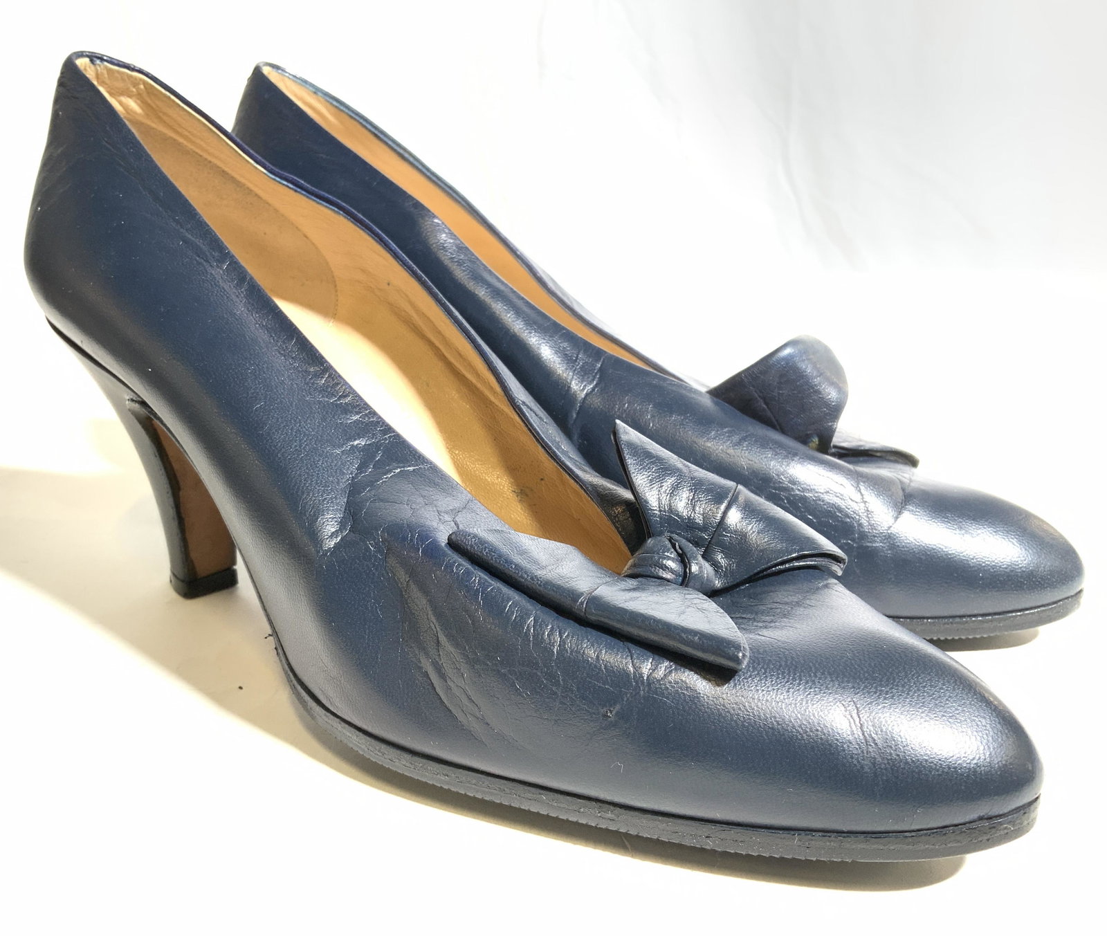 BOTTEGA VENETA Blue Leather Heels Size M: Soles of shoes read BOTTEGA VENETA. Each shoe is blue toned and appears to Be leather. Front of each shoe has bow shaped shoe ornament. Underside is inscribed M and also appears to possibly be inscrib