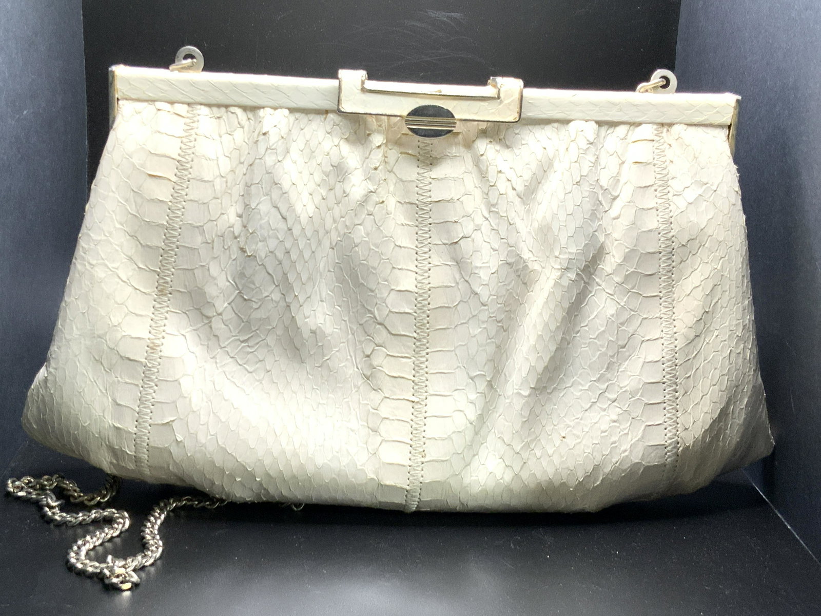Vintage Off White Snakeskin Shoulder Purse: A vintage off white toned snakeskin shoulder purse. Snap closure. Lined interior. Pockets to interior. Silver tone metal hardware, chain strap. Chain can be tucked away into the purse, can be worn as 