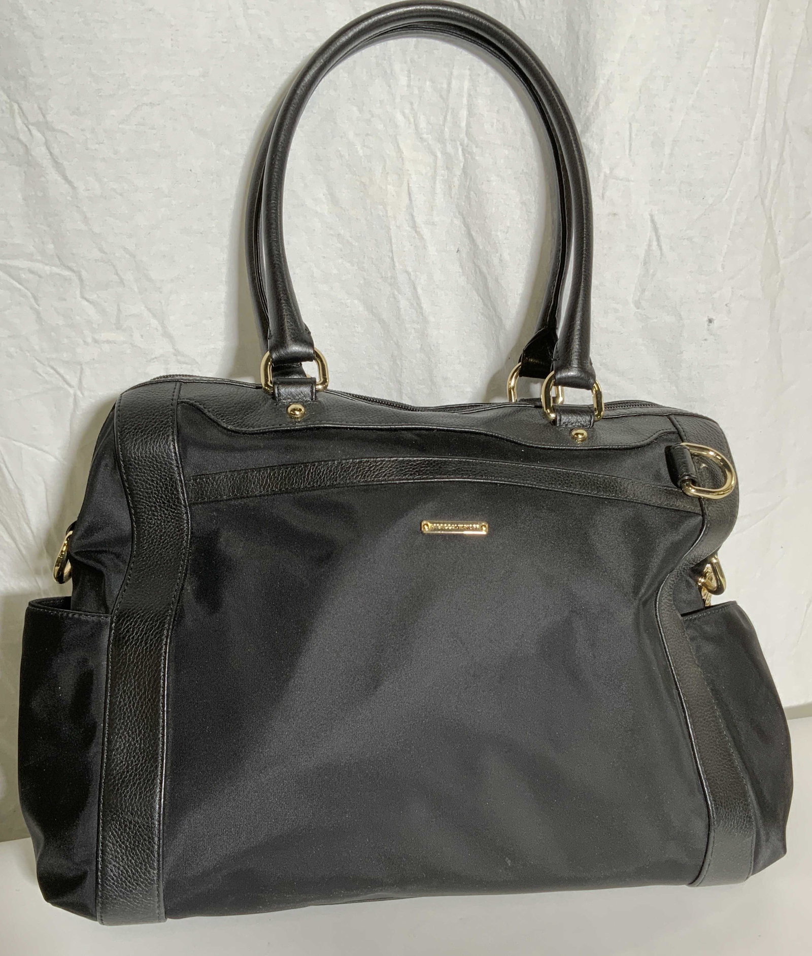 REBECCA MINKOFF Purse Black: Purse has gold toned metal ornament which is inscribed REBECCA MINKOFF. Purse is black toned and appears to possibly be leather & polyester. Piece has gold toned metal hardware. Each side has open ext