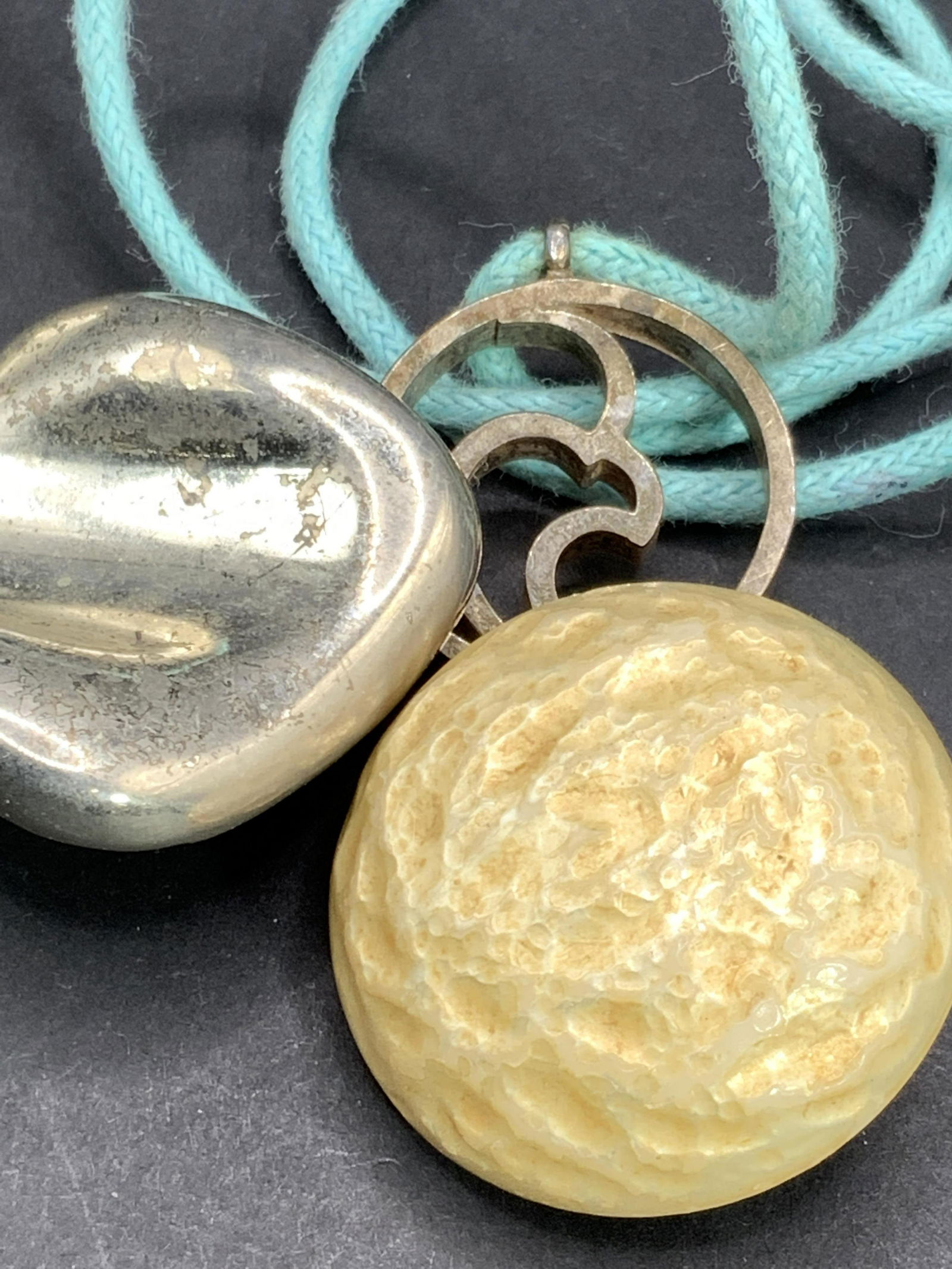 Lot 3 Vintage Pendant Necklace & Clip On Earrings: Two vintage button style statement piece clip on earrings. One crafted from silver tone metal, convex form. One crafted from composite material, circular form, impressed surface. Clip on backings. Pen