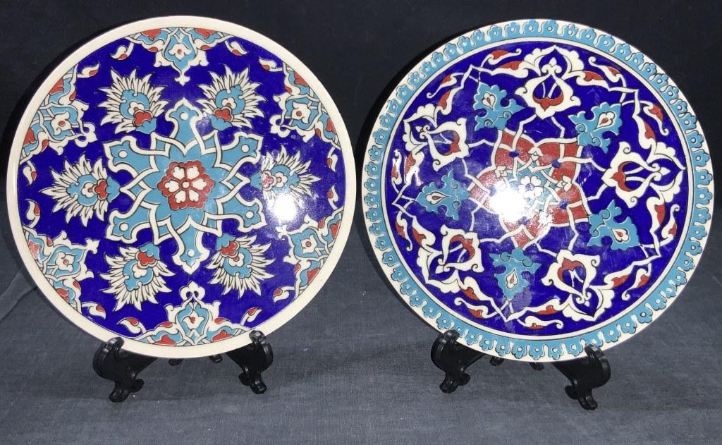 2 Ceramic Mosaic Vintage Trivets: 2 vintage ceramic trivets with mosaics style designs consisting of blues with red accents with white intersecting lines and floral motifs. Approximately 6.5 inches wide. Some chipping to edges. Vintag