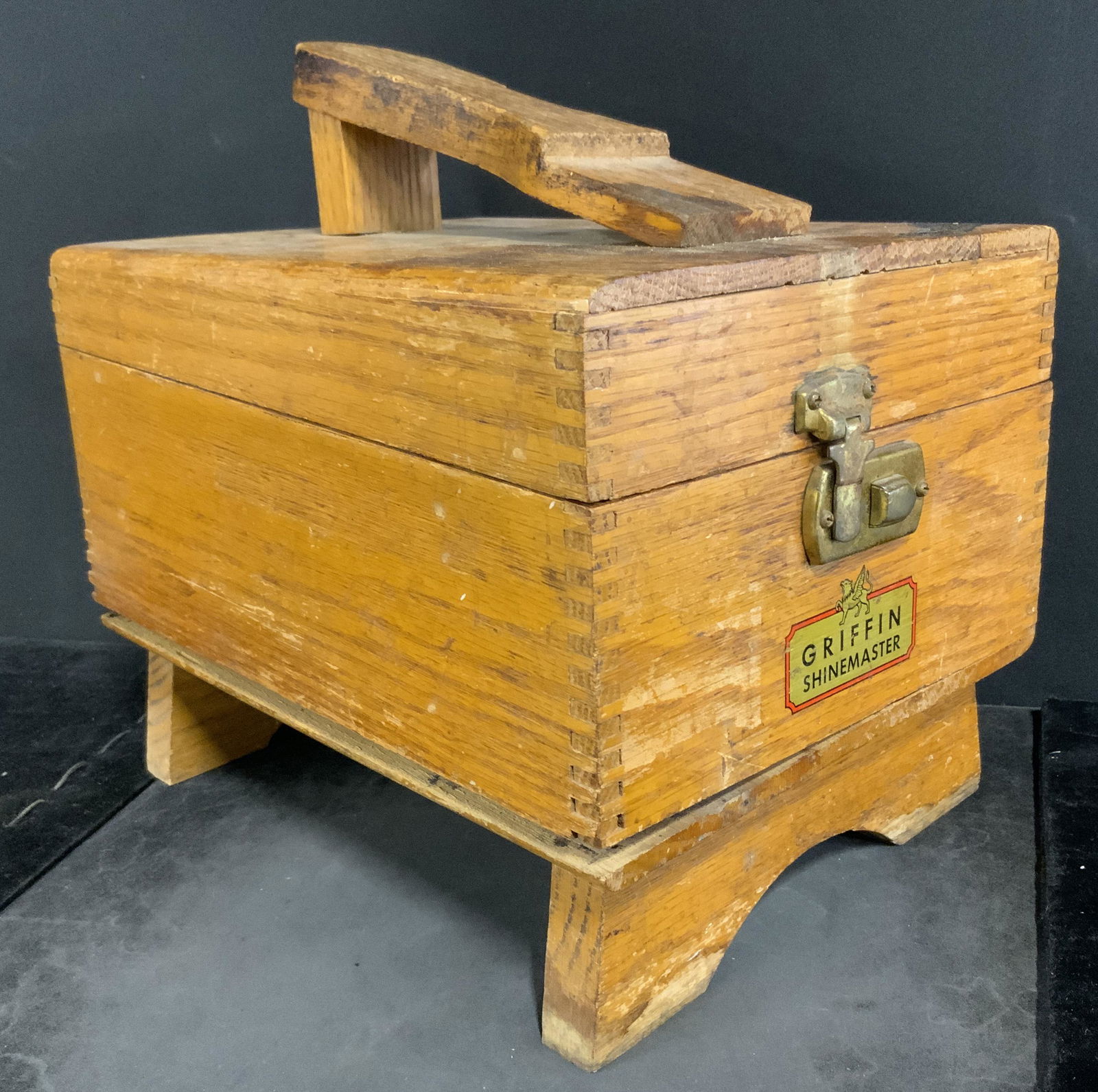 GRIFFIN SHINEMASTER Shoeshine Caddy w Brushes: Vintage shoeshine caddy, crafted from wood. Reads as Griffin Shinemaster. Includes 4 brushes. Lid secures with a brass clasp. Surface wear present, wood joints splitting, clasp sticks. Measures approx