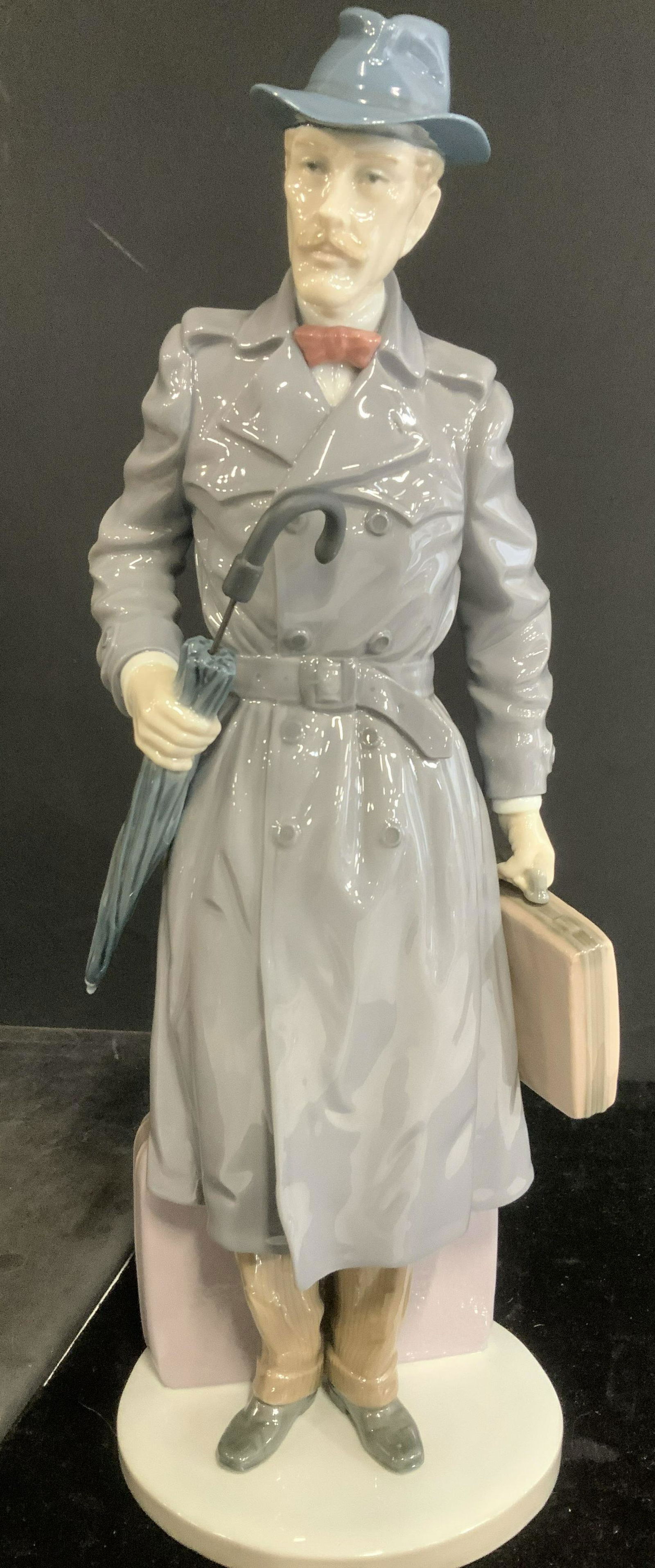 Lladro 5681 On the Road Porcelain Figural: Rare Lladro 5681 Porcelain Man wearing trench coat and hat, carrying an umbrella and briefcase, suitcase behind him Titled On The Road Man, Issued in 1990 and Retired in 1991. 14 in. Height, 4.5 in. W