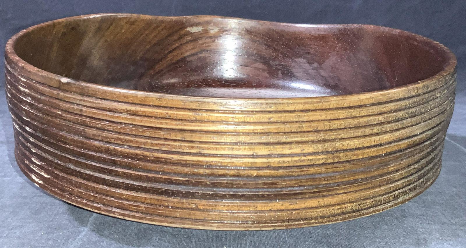 Signed Hand Crafted & Polished Wooden Bowl: Artist signed, hand crafted and Polished wooden bowl with exterior grooves, bowl is at slight angle. Polished in a reddish tone. Signed Patrick on underside. Approximately 4 inches tall and 9.25 inche
