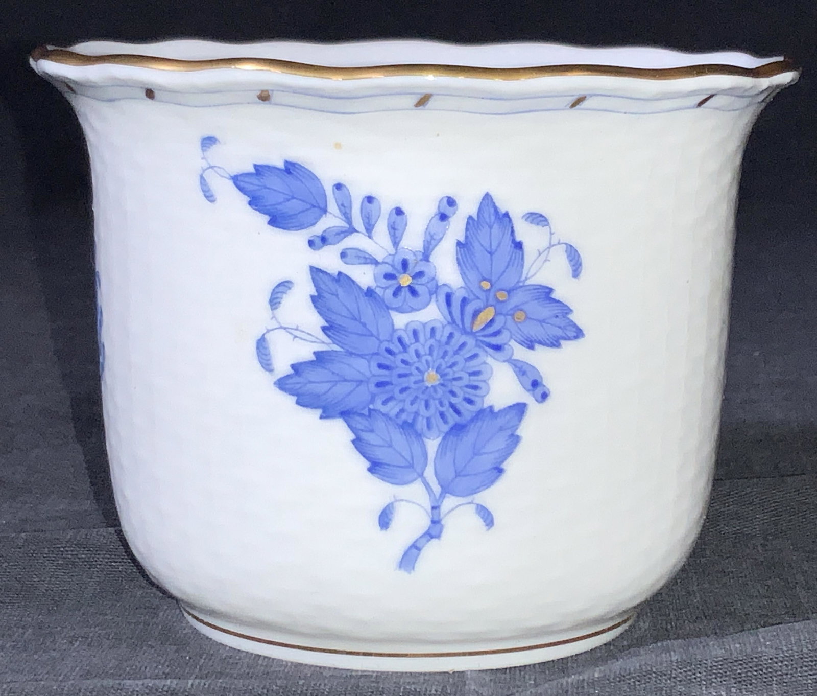 HEREND Hungarian Porcelain Cup: A white porcelain cup with gold gilt time and hand painted blue floral motifs on exterior, marked on underside Herend Hungary Hand painted 7305/AB v6 93. Exterior of the cup resembles a woven wicker, 