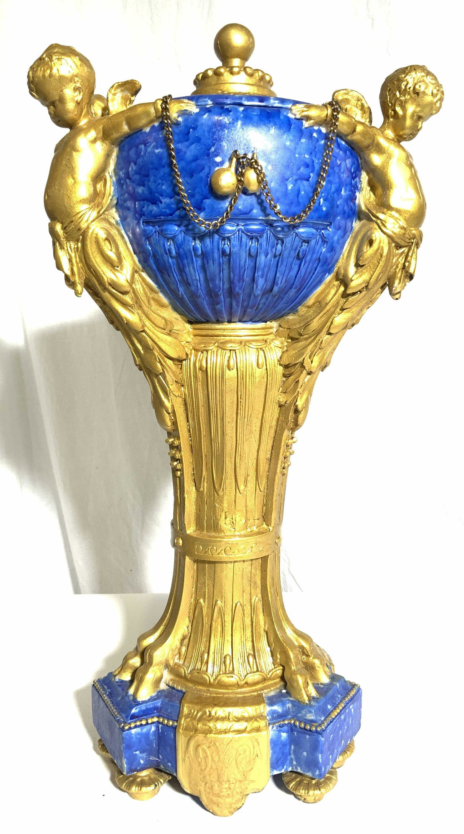 Ornate Neoclassical Composite Lidded Centerpiece: Centerpiece is ornately detailed with neoclassical style. Piece has gold gilt cherub & hoof detail. Base of structure is footed. Piece has painted blue toned areas. Base has small beaded detail. Piece