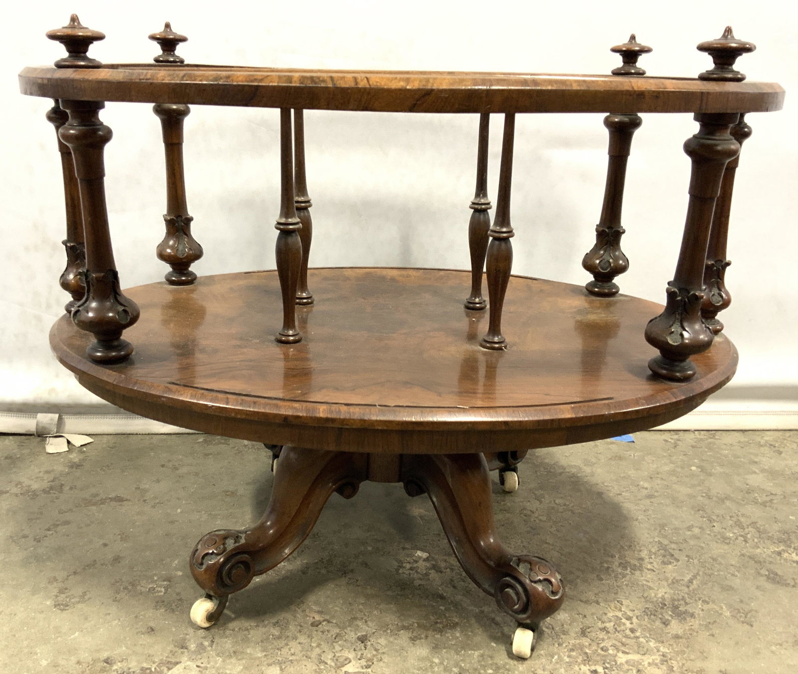 Vintage Carved Wooden Canterbury On Casters: Canterbury is vintage possibly antique. Piece is wooden with intricately carved wooden legs which sit atop cream toned casters. Canterbury swivels. Piece also has carved wooden pillar style structures