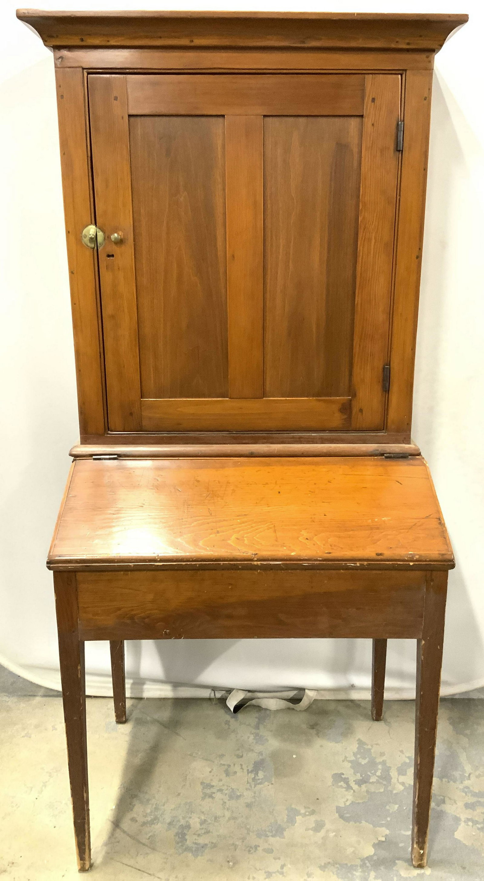 Vintage Carved Wooden Secretary Desk: Secretary desk is vintage possibly antique. Piece is wooden. Lower half has flip open area with cubby spaces inside. Upper half has cabinet door area with 2 wooden shelves inside. Desk is possibly han