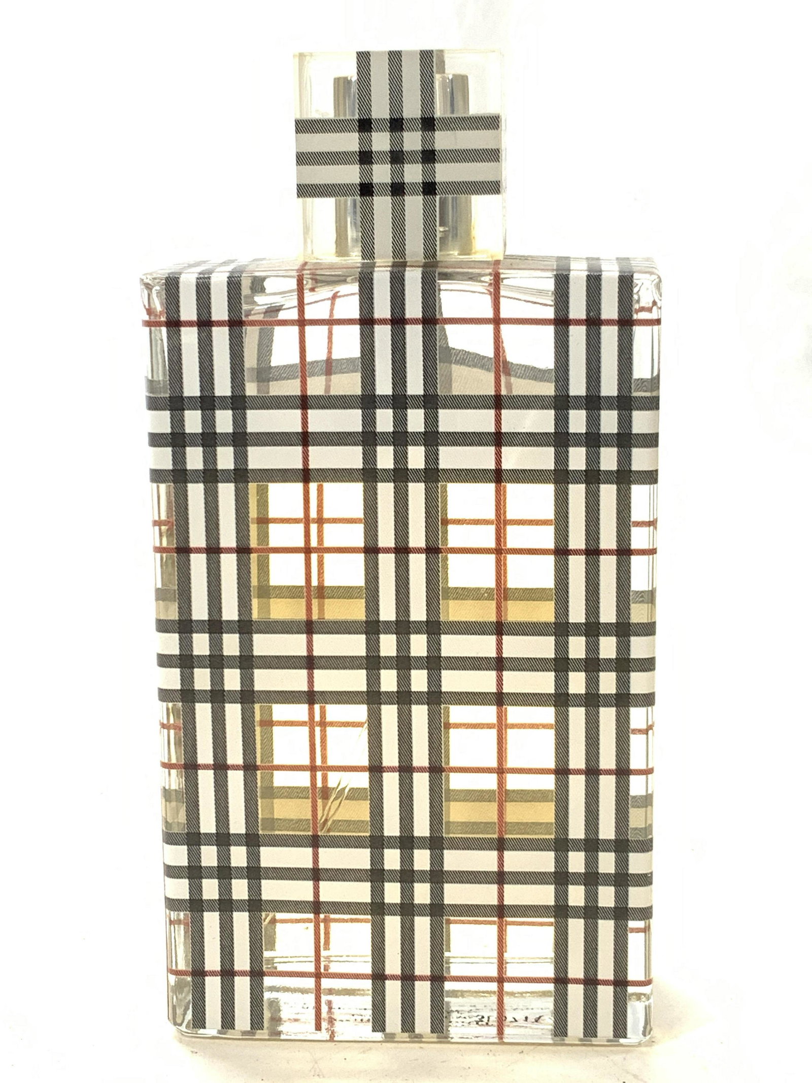 BURBERRY Brit Inter Parfum, France: Bottle of Burberry Brit. Bottle is rectangular with a square cap and adorn with gray, white and red plaid pattern over the clear glass bottle. Marked on underside Burberry Brit Inter Parfum 4 Rd pt ch