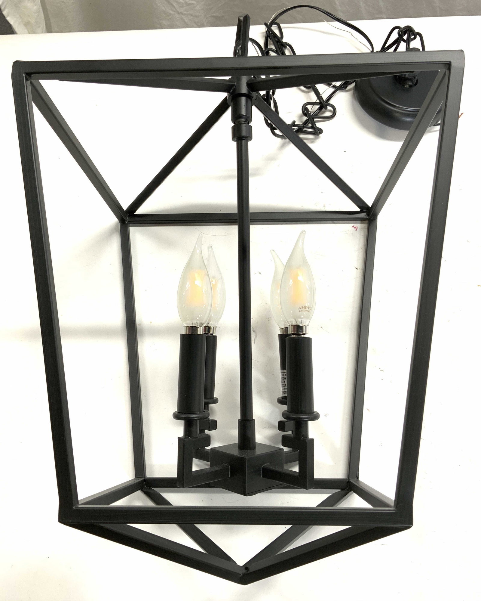 AMDTU LIGHTING Metal 4 Arm Chandelier: Bulbs are marked AMDTU LIGHTING. Chandelier is black toned and metal. Piece has swinging structure with 4 arms attached. Each arm has candlestick. Piece hangs from chain link. 54 inches tall with chai