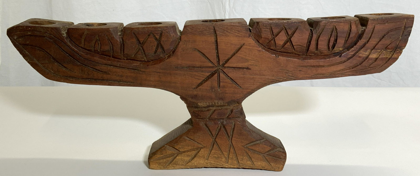 Vintage Carved Wooden Candelabra: Candelabra is vintage and wooden. Piece has 7 candle holding areas. Candelabra has carved detail within structure. Piece measures approx 6 inches long 6 inches tall 1.75 inches deep. Candelabra, woode