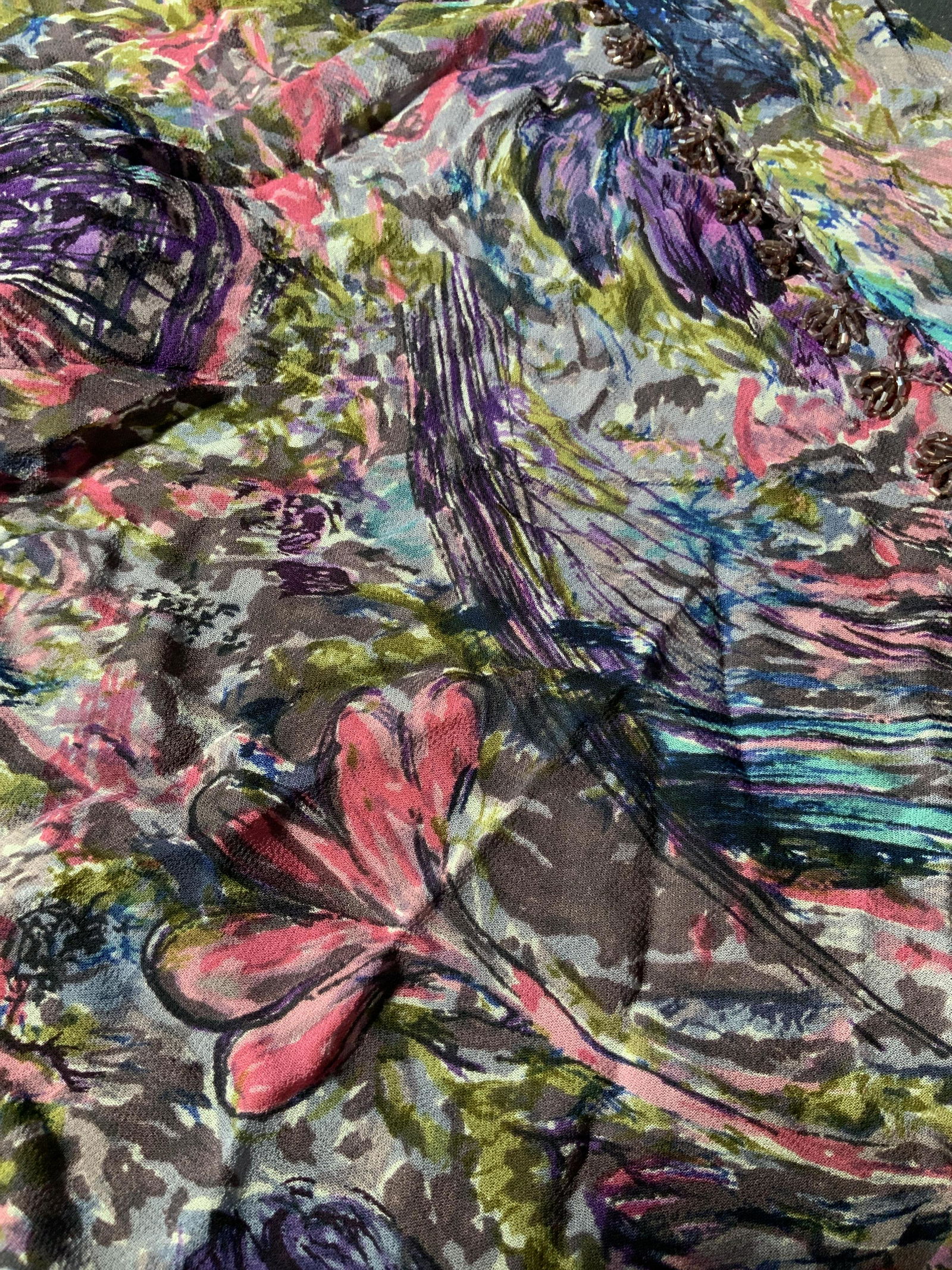 ATG Triangular Beaded Fringe Scarf: A triangular scarf possibly a scarf to be worn around the waist for belly dancing, with a an abstract floral motif with purple glass beads on fringe, with tag that reads ATG All that glitters of San F