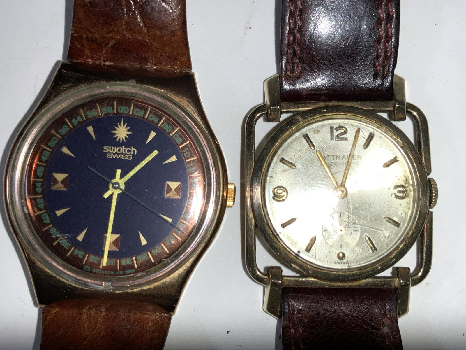 Lot Of 2 Vintage Swiss Made Watches, GF: A group lot of 2 Swiss made wrist watches. 1 marked Swatch with a gold toned face with a rust orange toned metal on interior face of watch, wrist band resembles reptile skin, and marked Swatch, genuin