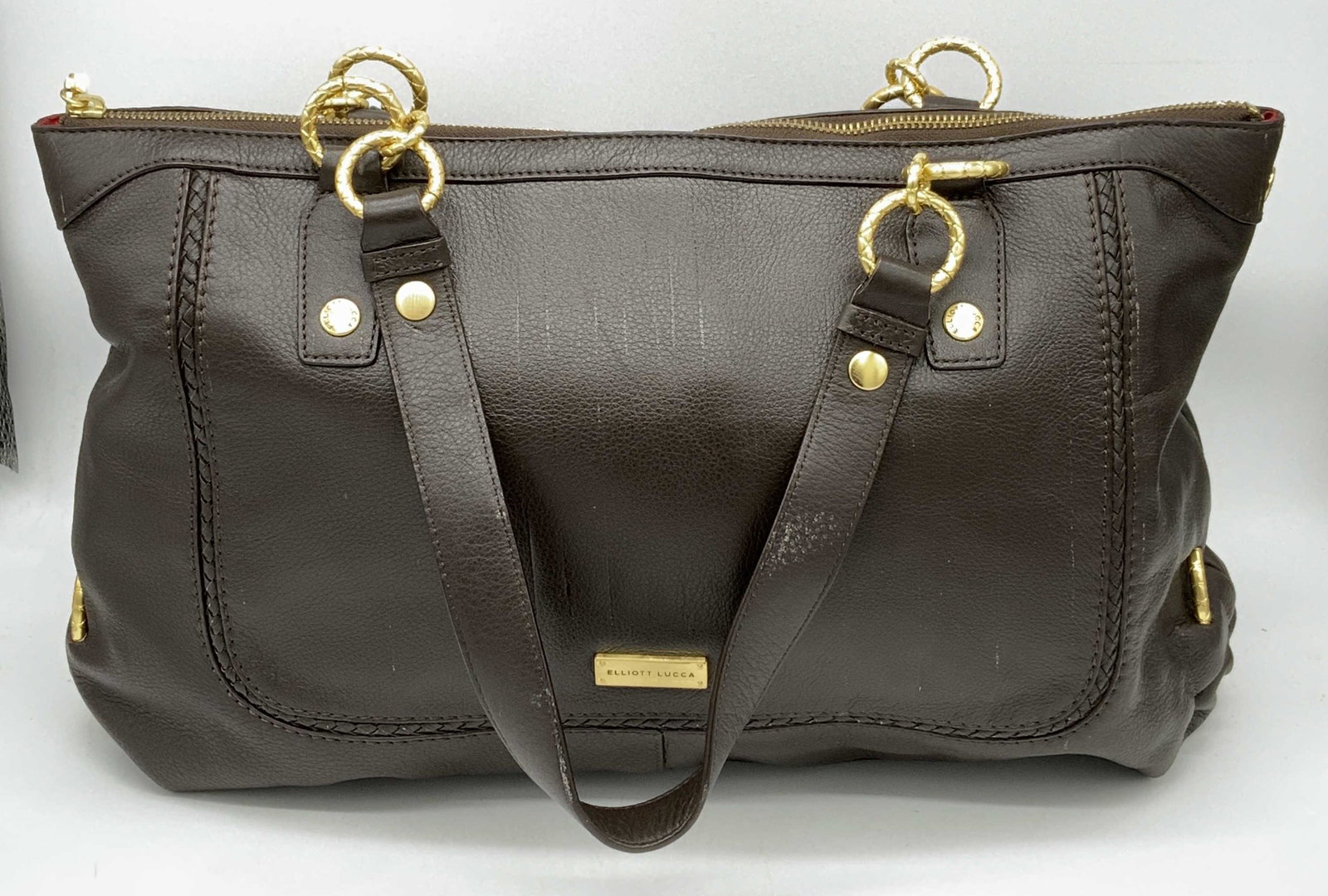 ELLIOT LUCCA Leather Shoulder Bag: ELLIOT LUCCA Leather Shoulder Bag, brown leather exterior with gold toned hardware, zipper closure, main interior compartment has red polyester lining with Elliot Lucca insignia, two pockets, and one