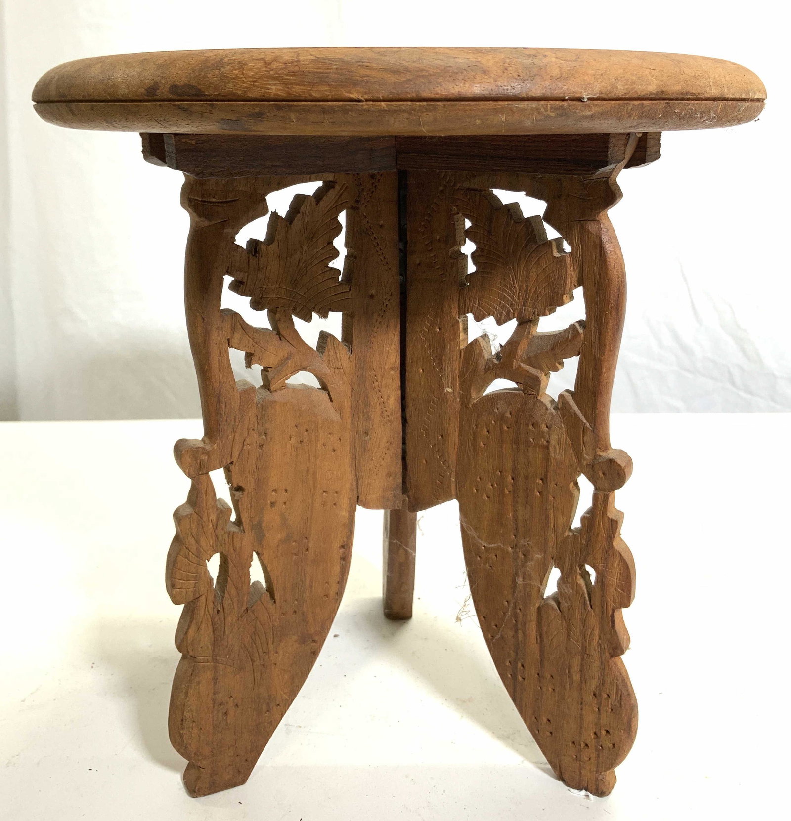 Vintage Carved Wooden Morrish Stool Table: Stool is vintage and wooden. Piece has intricately carved floral, vine, & leaf detail. Piece has 3 leg pedestaled base. Center of top has bone inlay detail. 9.5 inches tall 9 inches wide. Stool, moori