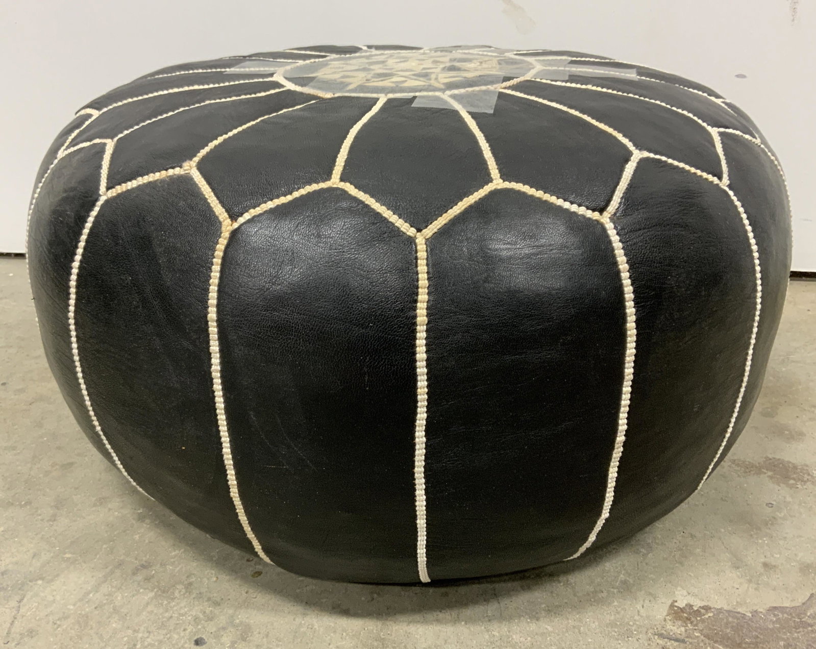 Black Floor Pouf Ottoman: Black floor pouf. Tearing present, tape present. Measures approx 11 inches h and 21 inches w. Home decor, ottoman, foot stool, decorative accessories, decorative arts, vintage decor. 9x